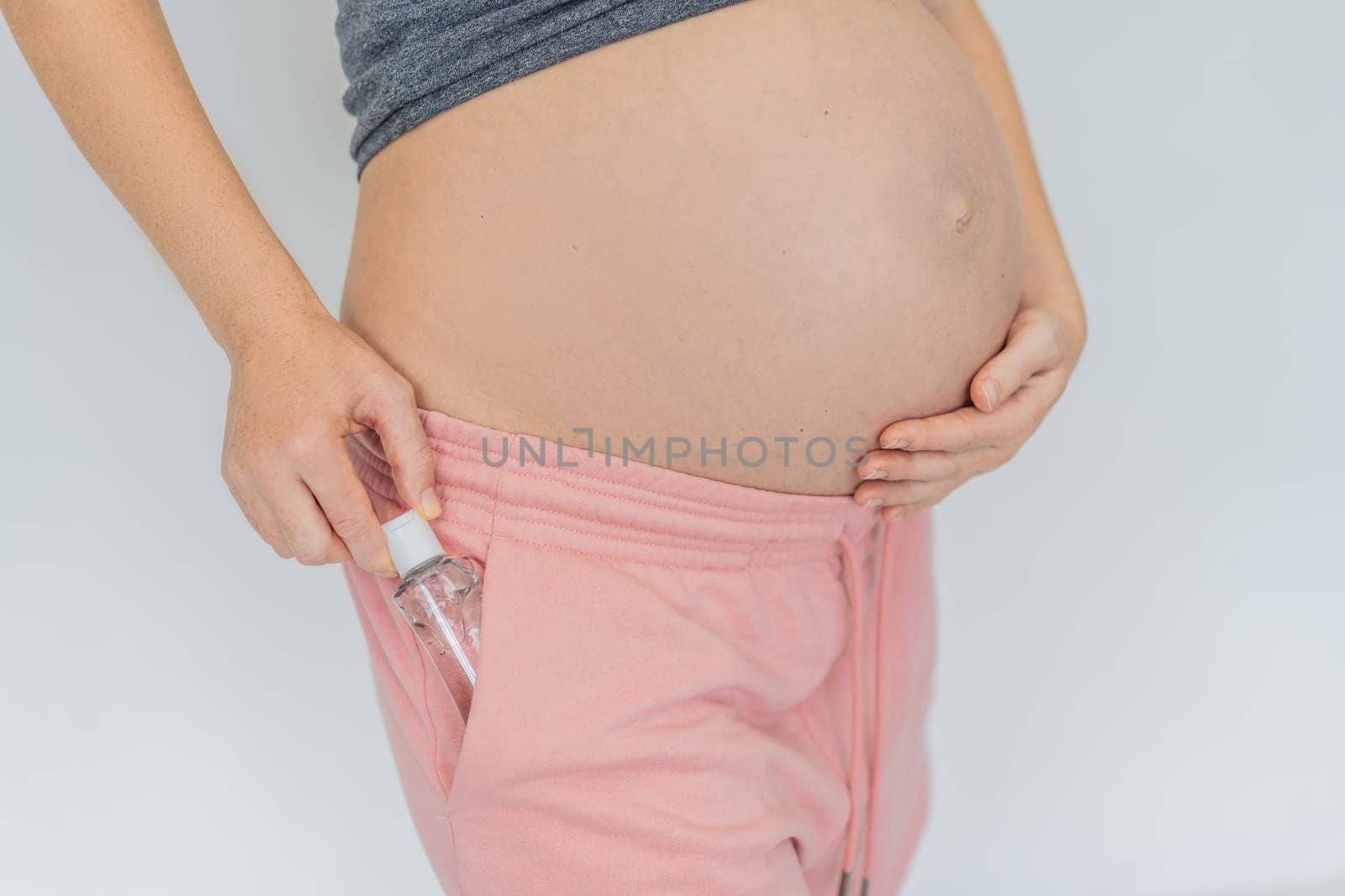Expectant mom ensures safety, applying gel sanitizer for a clean and healthy pregnancy by galitskaya