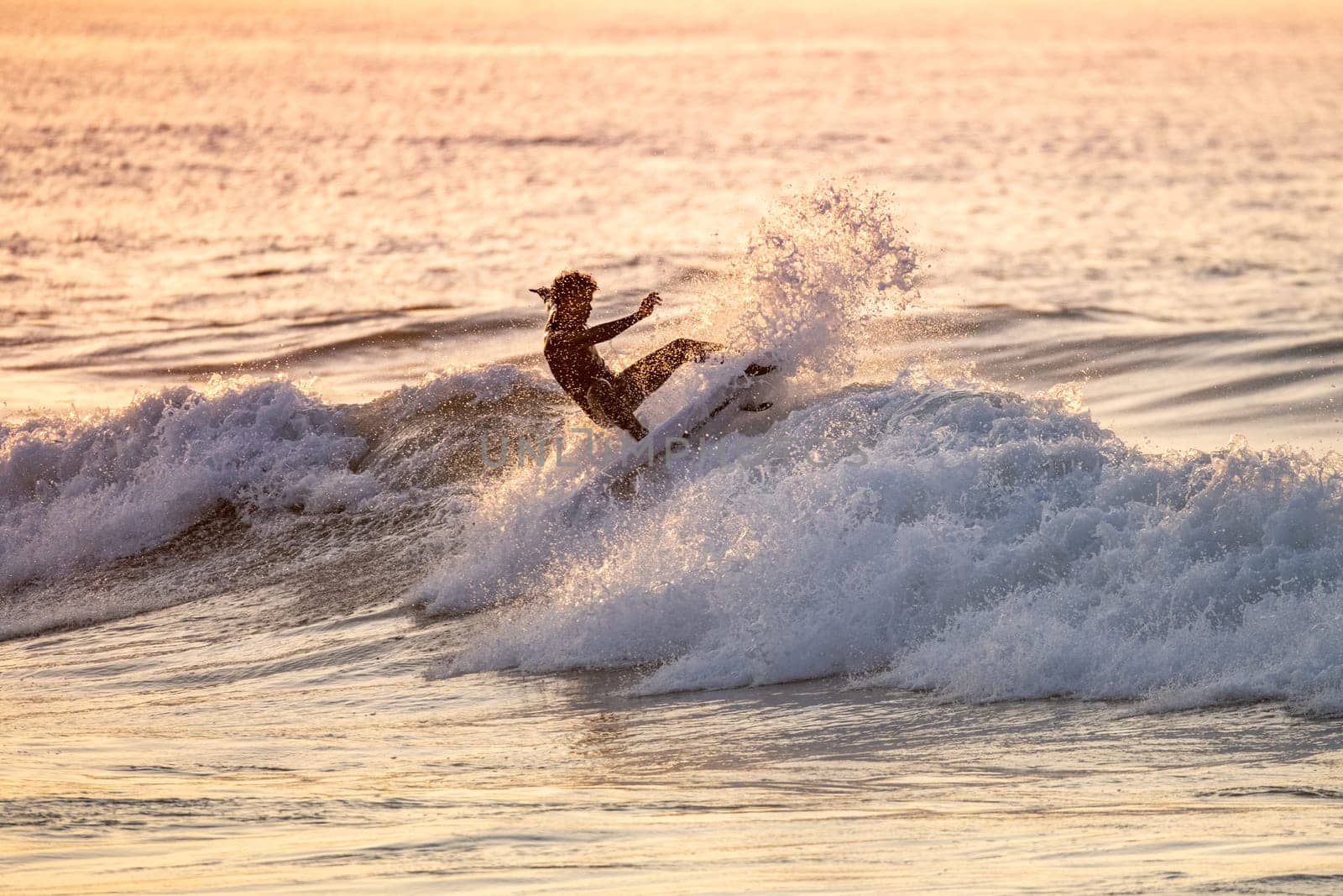 Sporty boy riding his surf board on the ocean wave.