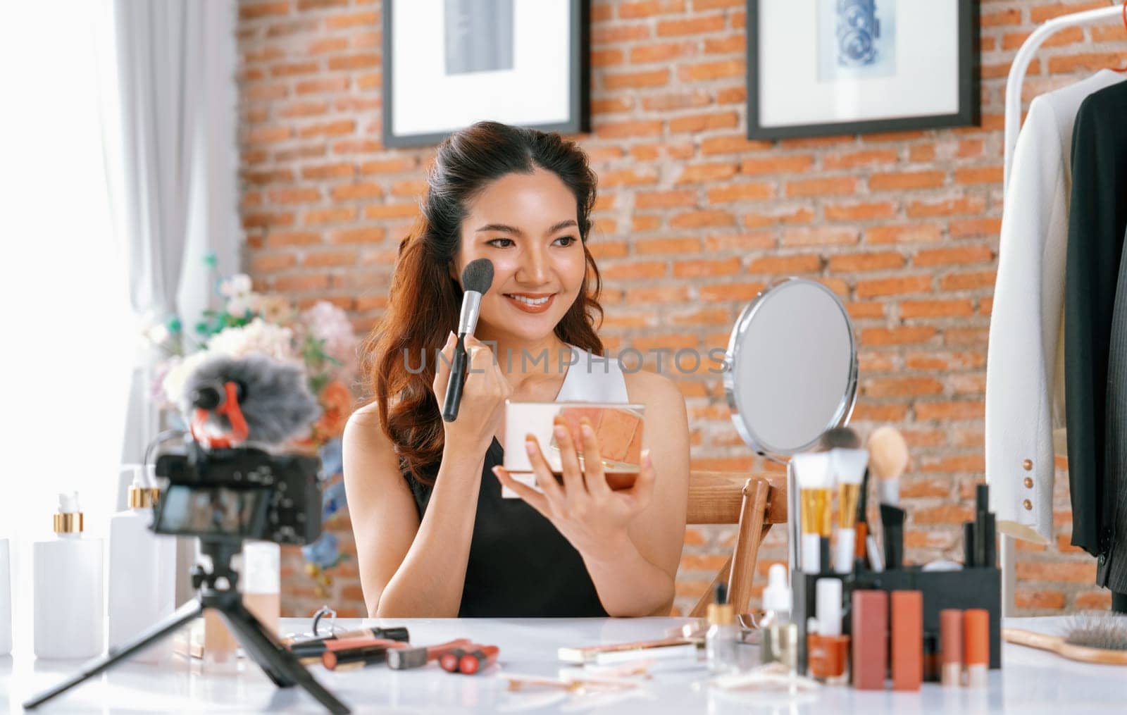 Asian Woman influencer shoot live streaming vlog video review makeup uttermost social media or blog. Happy young girl with cosmetics studio lighting for marketing recording session broadcasting online