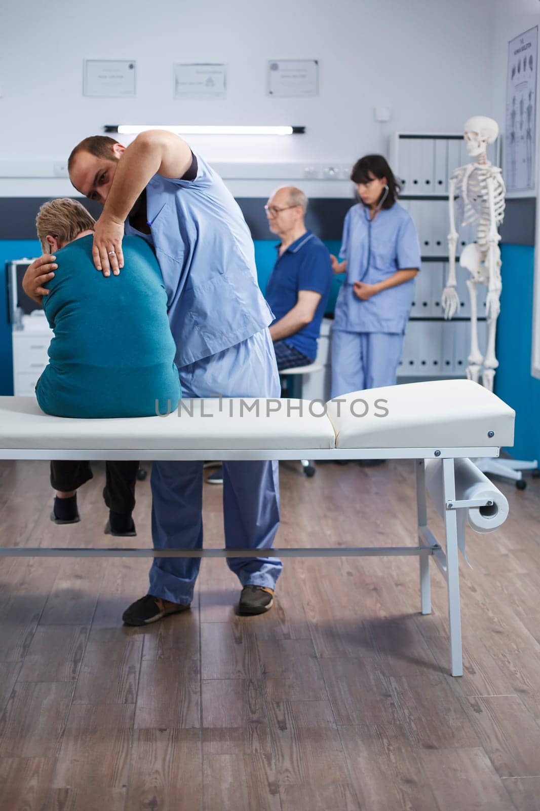Osteopathy specialist relieving pressure from back bones of senior patient for physiotherapy. Doctor giving support and helping old woman with spinal cord ache for physical recovery.
