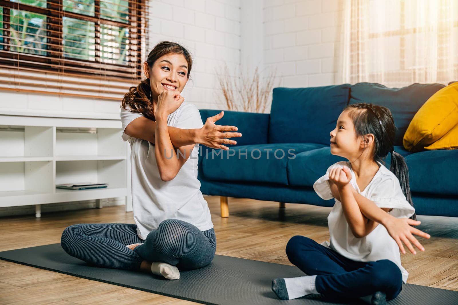 In the gym a mother and her daughter embrace stretching and yoga promoting togetherness strength and happiness radiating smiles and positivity in their family fitness routine.