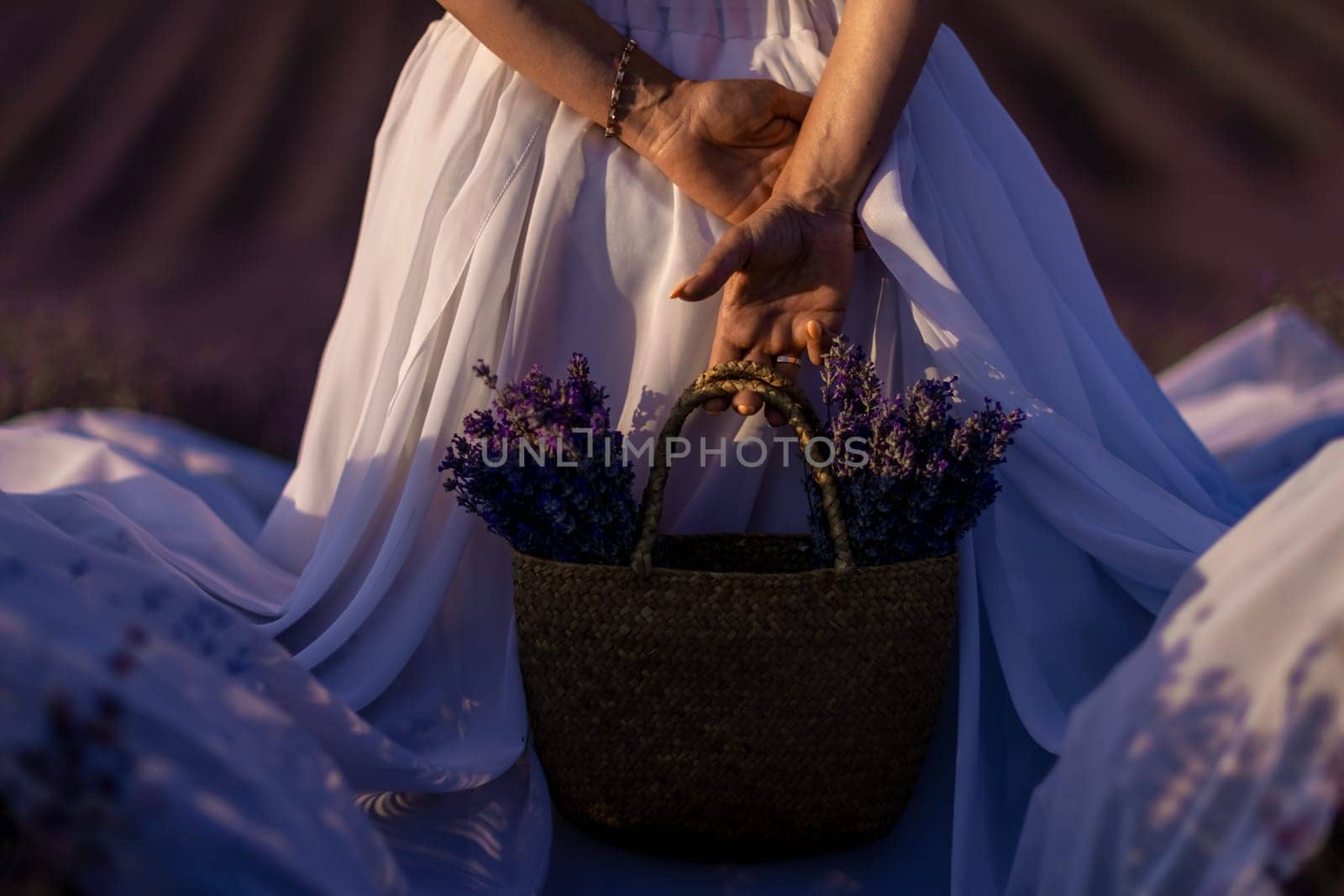 Back view woman lavender sunset. Happy woman in white dress holds lavender bouquet. Aromatherapy concept, lavender oil, photo session in lavender.