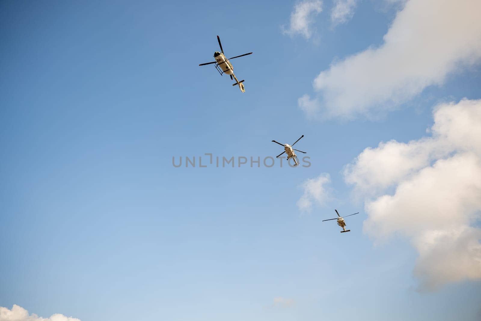 Flying helicopter against blue sky showcasing modern technology. New turbine engine hovering rescue and ambulance capabilities. Pilot controls small aircraft in flight exhibition. by Sorapop