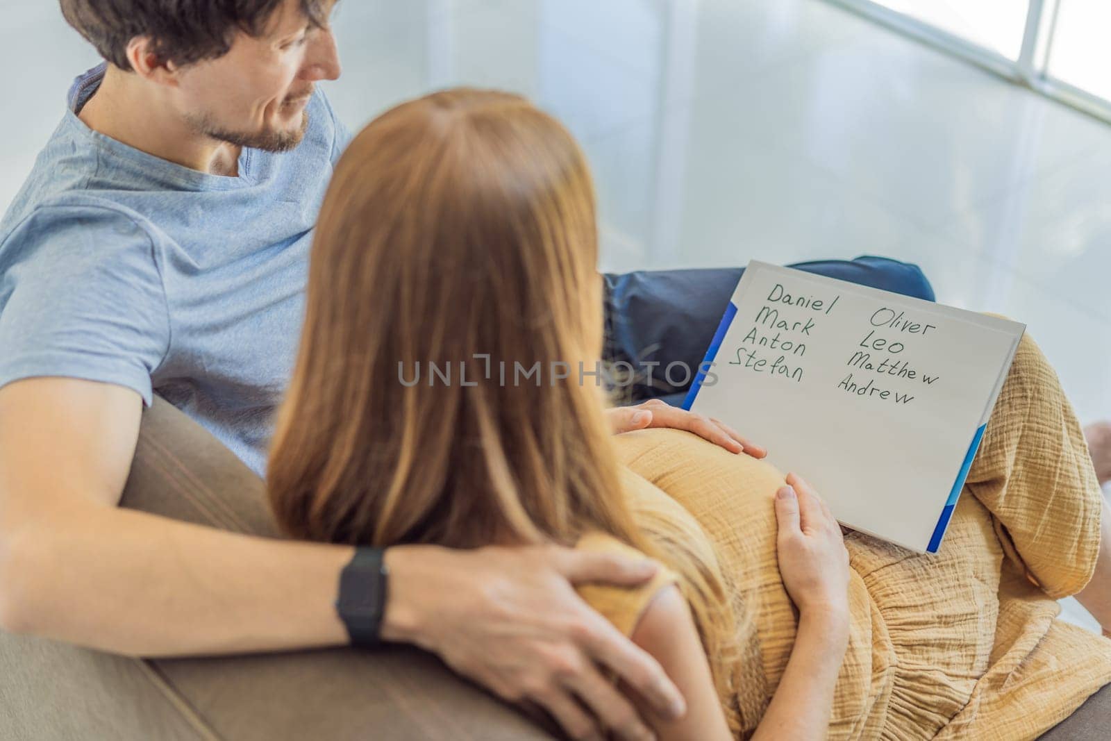 Expectant couple joyfully selects a name for their unborn son, savoring the special moment of choosing a meaningful identity for their growing family.