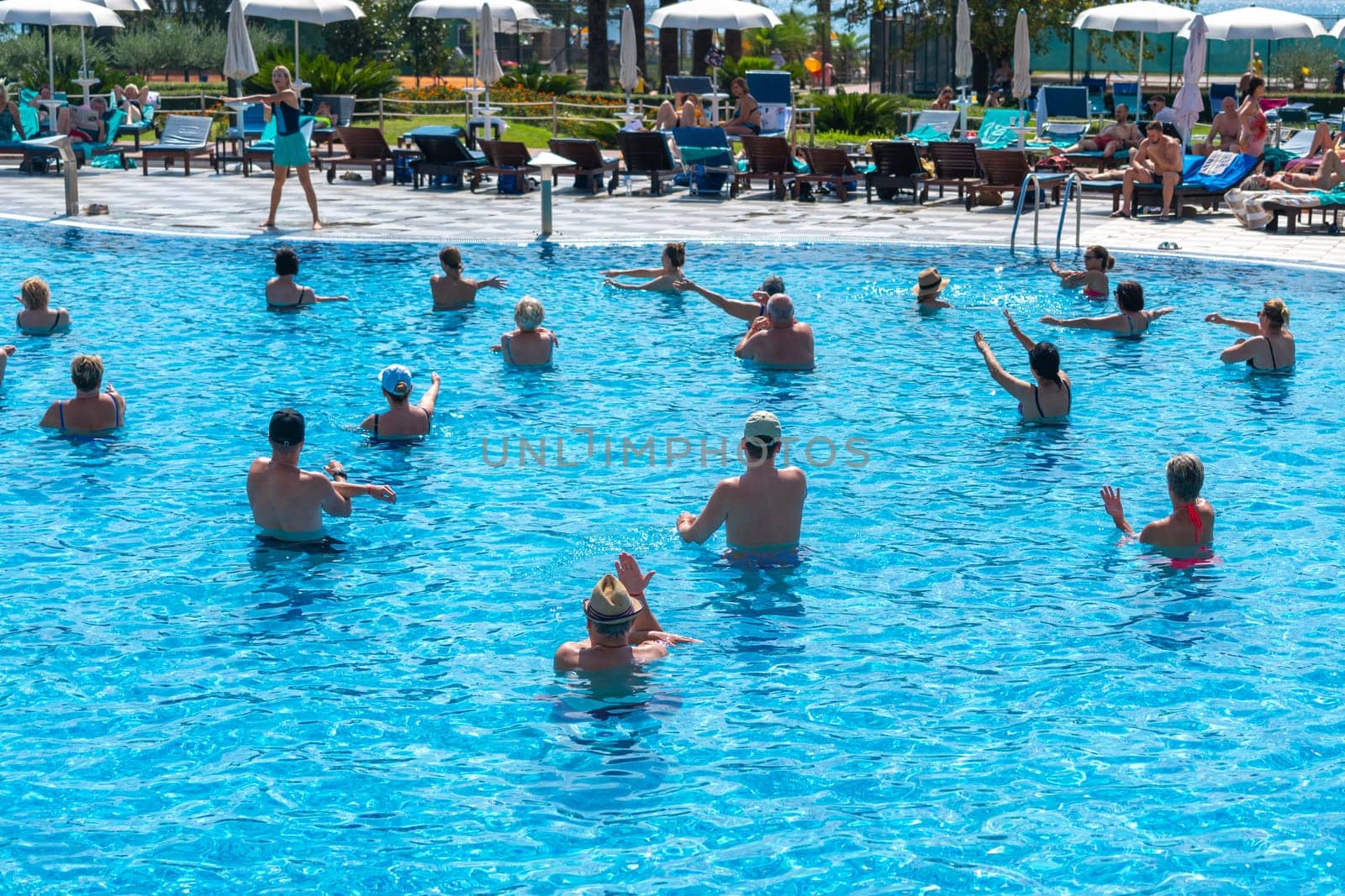BUDVA, MONTENEGRO - SEPTEMBER 08, 2023: Morning aqua aerobics session in full swing at a hotel pool. Concept of energizing start and group fitness by Mariakray