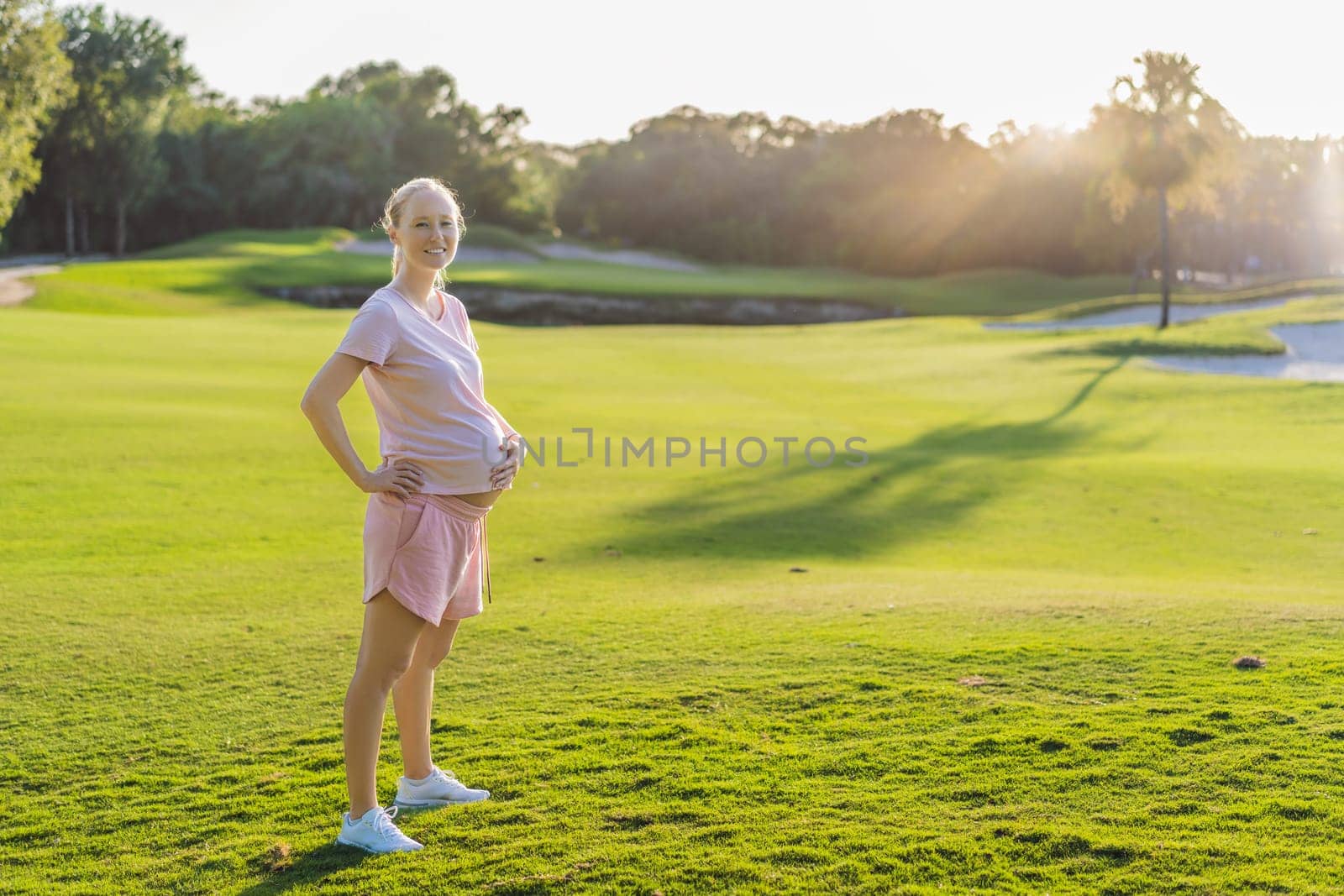 Energetic pregnant woman takes her workout outdoors, using an exercise mat for a refreshing and health-conscious outdoor exercise session.