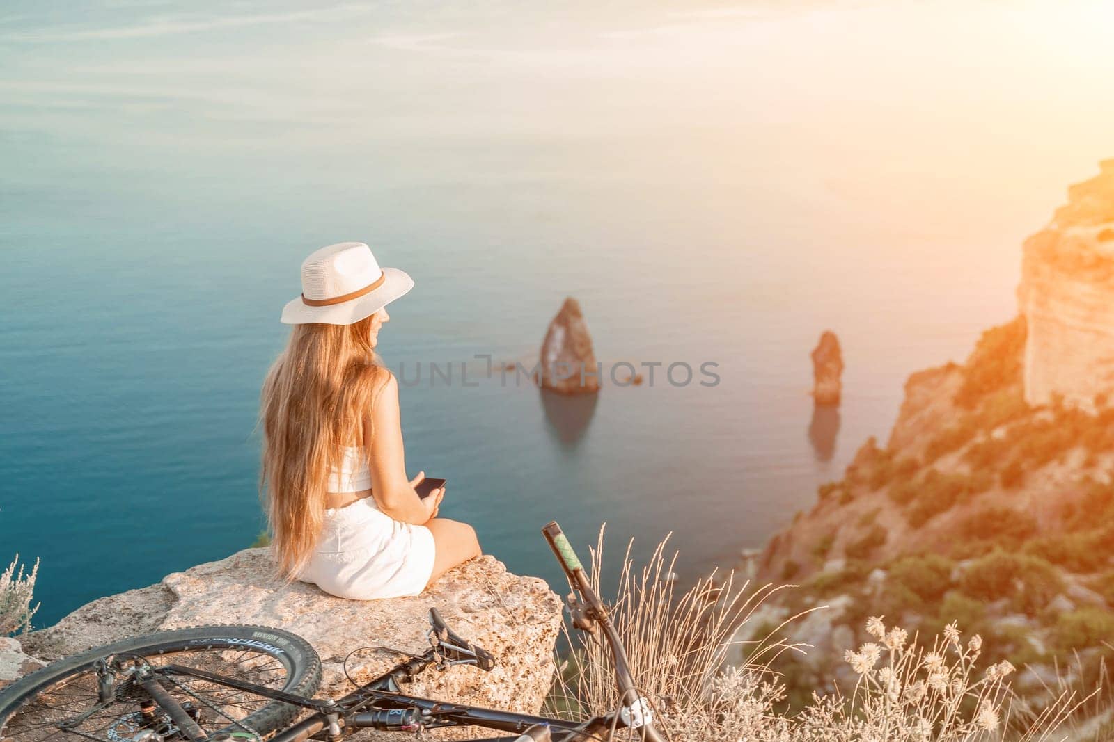 A woman cyclist on a mountain bike looking at the landscape sea. by Matiunina