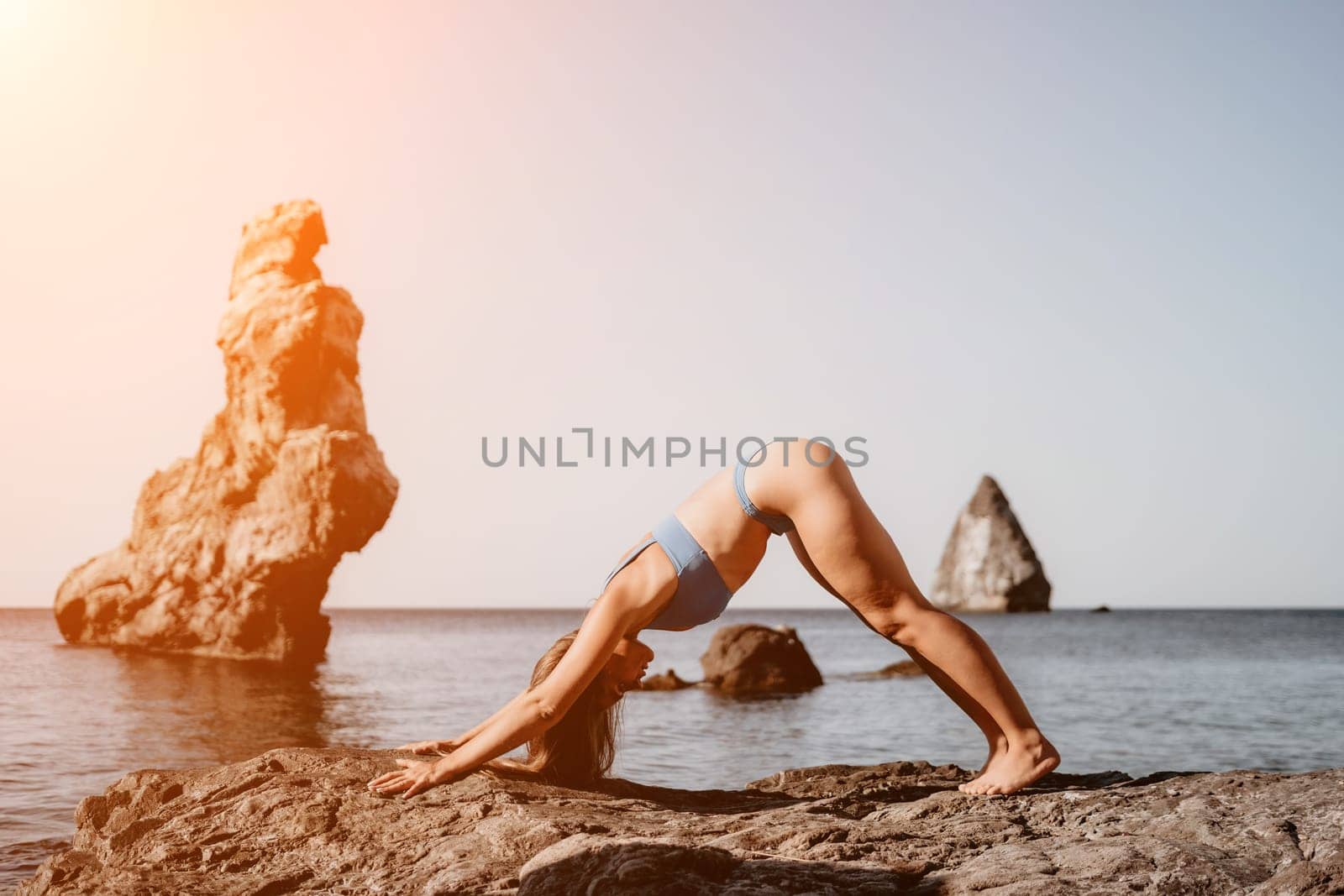 Middle aged well looking woman with black hair doing Pilates with the ring on the yoga mat near the sea on the pebble beach. Female fitness yoga concept. Healthy lifestyle, harmony and meditation.