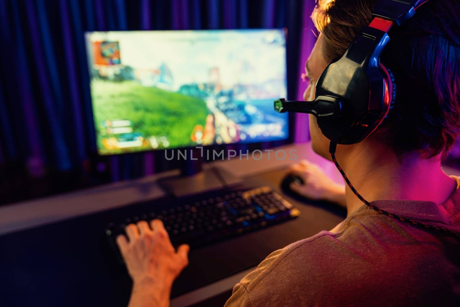 Host channel of smart gaming streamer, playing battle team shooting gun with multiplayer or single at warship on screen at back side view, wearing headset at digital neon light cyber room. Pecuniary.