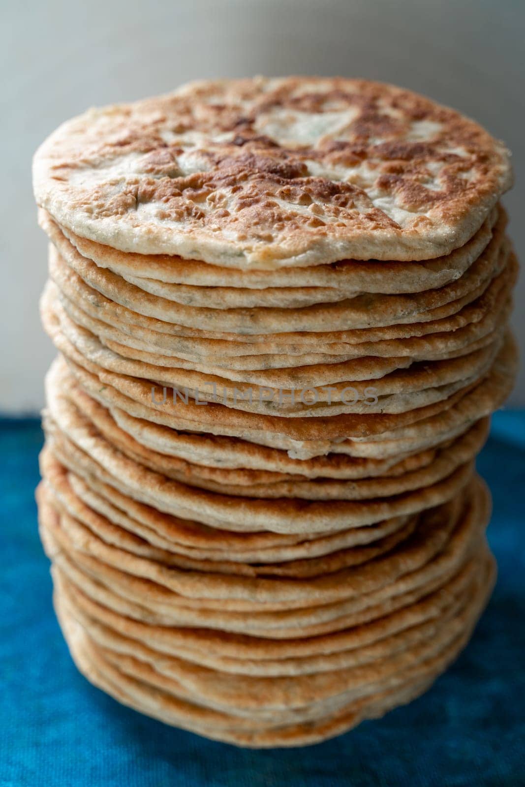 Flatbread lavash, chapati, naan, heap of tortilla on a blue background Homemade flatbread stacked. by Matiunina
