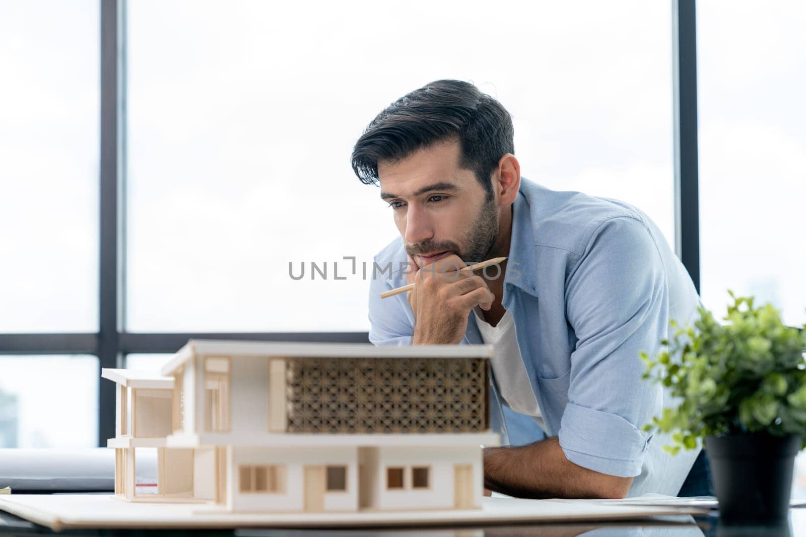 Smart civil architect engineer looking while planing design house construction with blueprint, house model and architectural equipment. Designer measuring and inspecting house model. Design. Tracery.