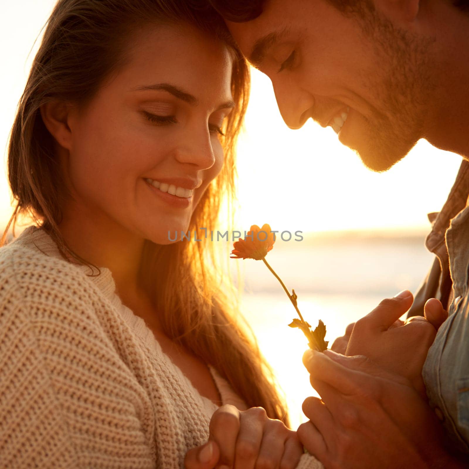 Flower, smile and young couple at beach on vacation, adventure or holiday for valentines day. Love, sunset and man and woman with floral plant by ocean for tropical weekend trip on romantic date