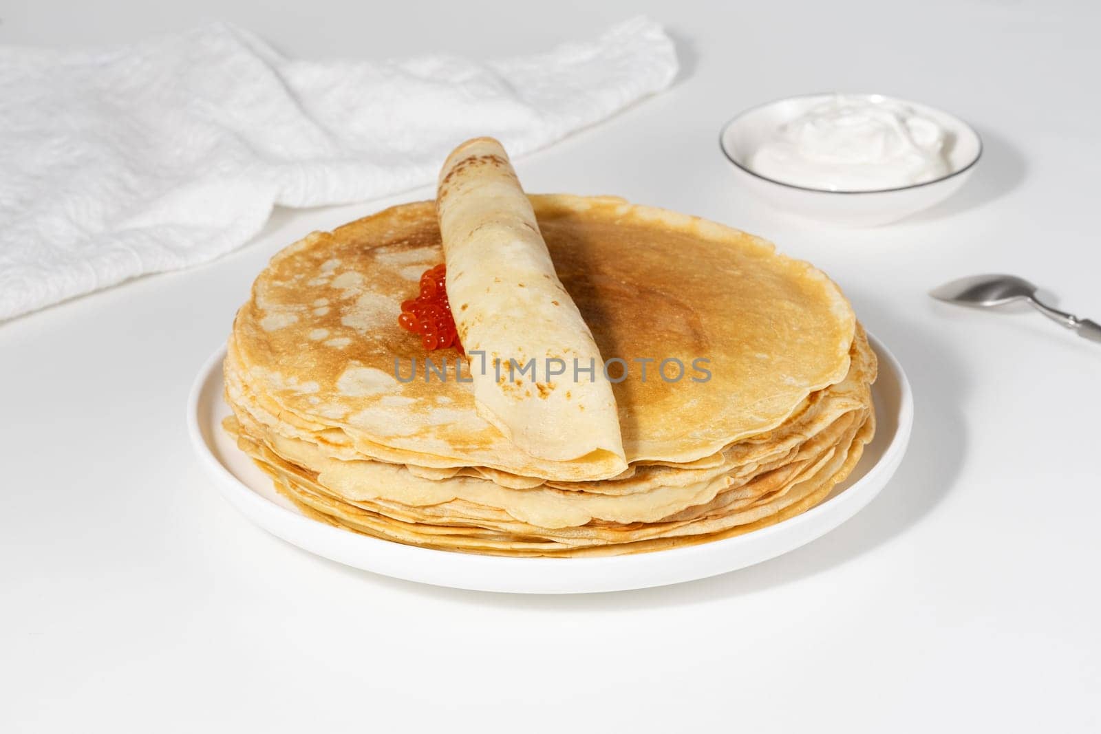 Pancakes with red caviar. Close-up of pancakes stacked on white background.