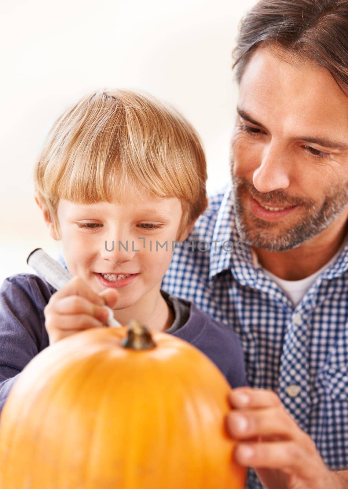 Child, father and drawing on pumpkin for halloween, craft and celebrate party at home. Happy boy kid, dad and family writing with pen marker on vegetable for holiday lantern, decoration or creativity by YuriArcurs