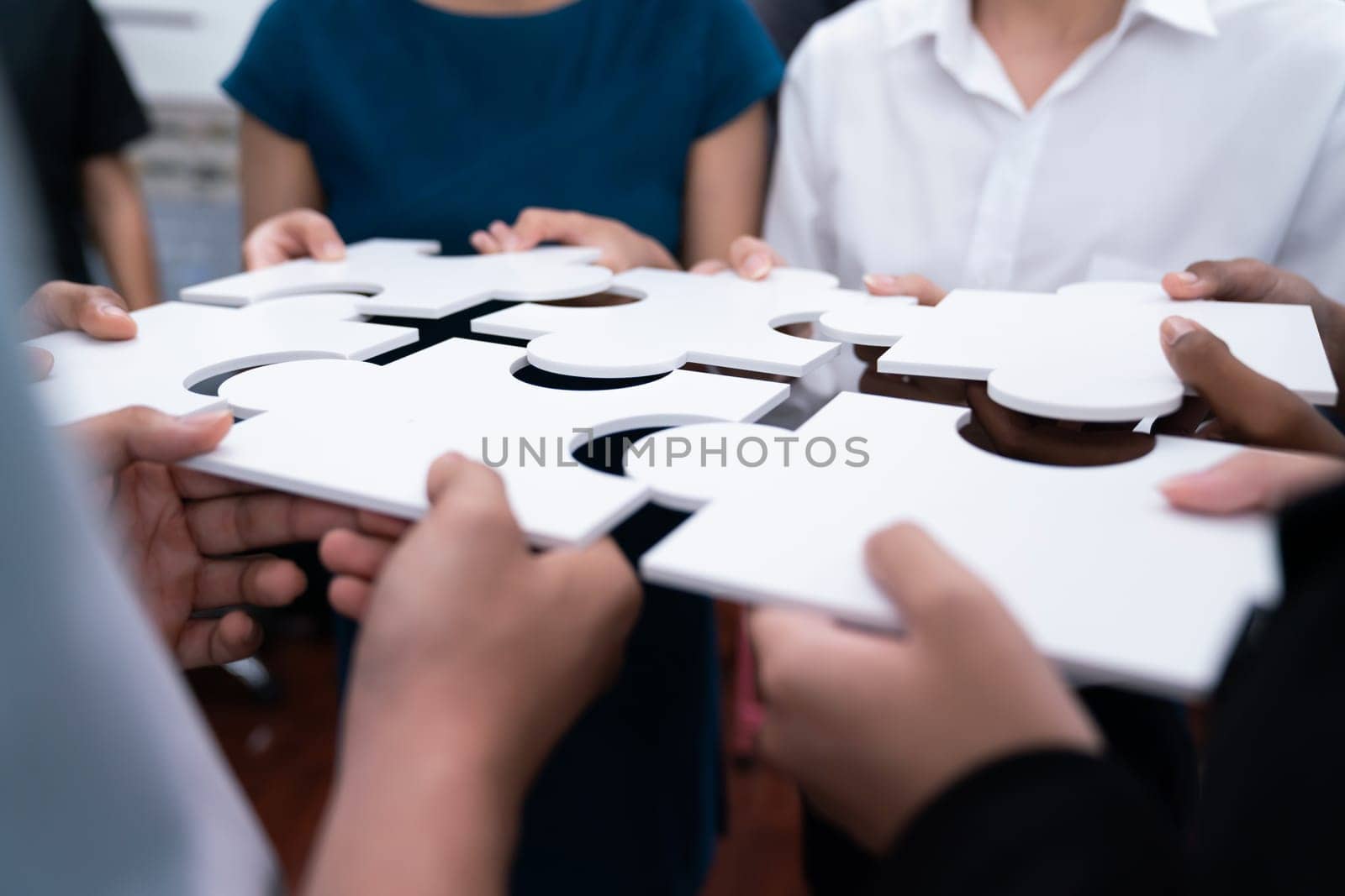 Diverse corporate officer workers collaborate in office, connecting puzzle pieces to represent partnership and teamwork. Unity and synergy in business concept by merging jigsaw puzzle. Concord