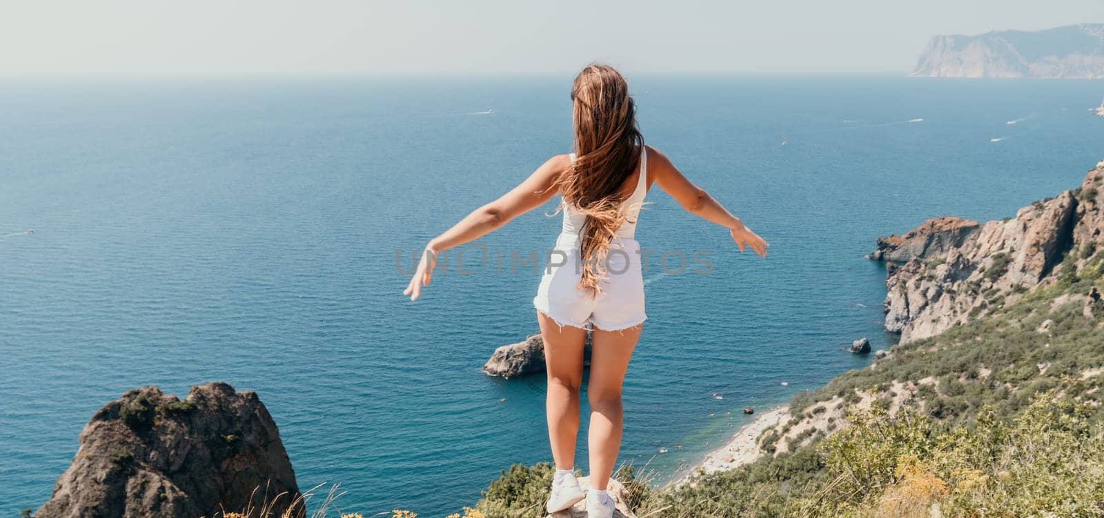 Woman summer travel sea. Happy tourist enjoy taking picture outdoors for memories. Woman traveler posing over sea bay surrounded by volcanic mountains, sharing travel adventure journey by panophotograph