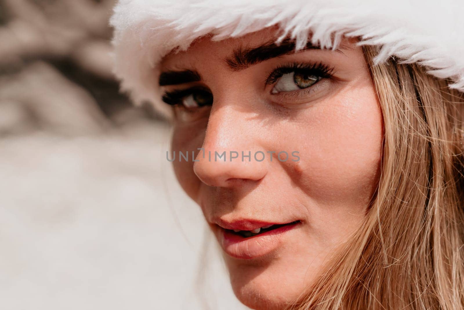 Woman summer travel sea. Happy tourist in red bikini and Santas hat enjoy taking picture outdoors for memories. Woman traveler posing on the beach surrounded by volcanic mountains, sharing travel joy by panophotograph