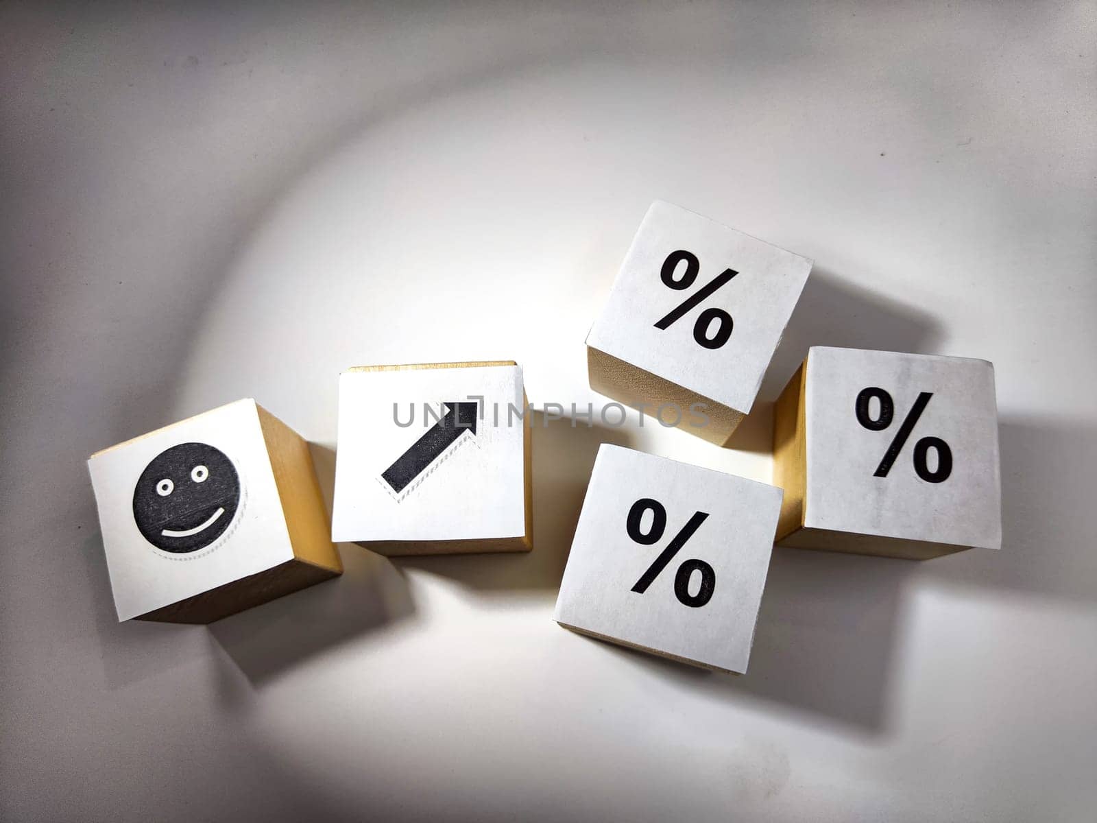 Wooden cubes in a column and row with white signs with a smiley sign, an arrow, a percentage. The concept of positivism. Positive thinking leads to the achievement of results and profits