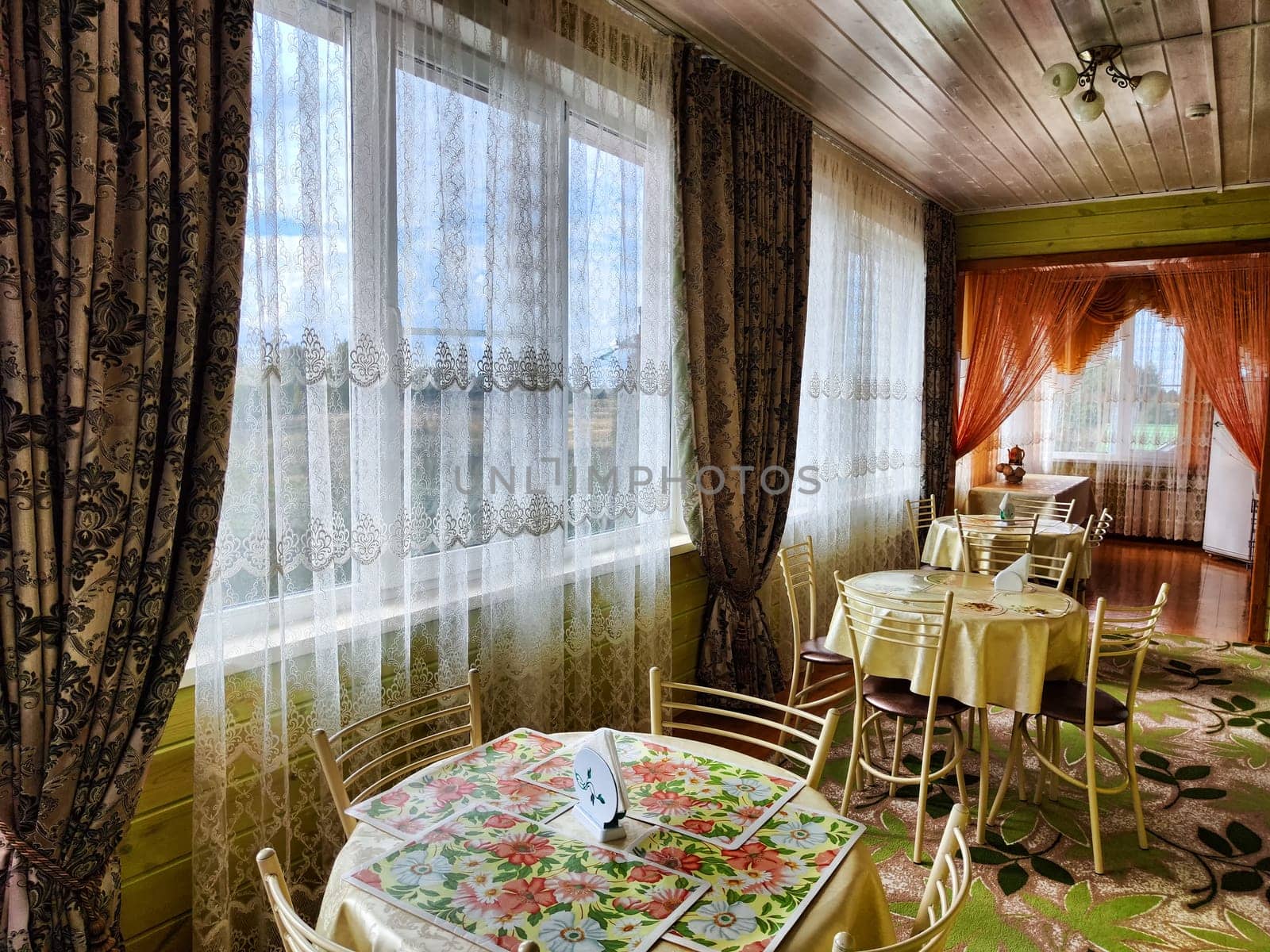 A table in a small cozy cafe or restaurant with window and curtains. Dimmed lights, beautiful Design of the hall. Nobody to a place to relax and eat