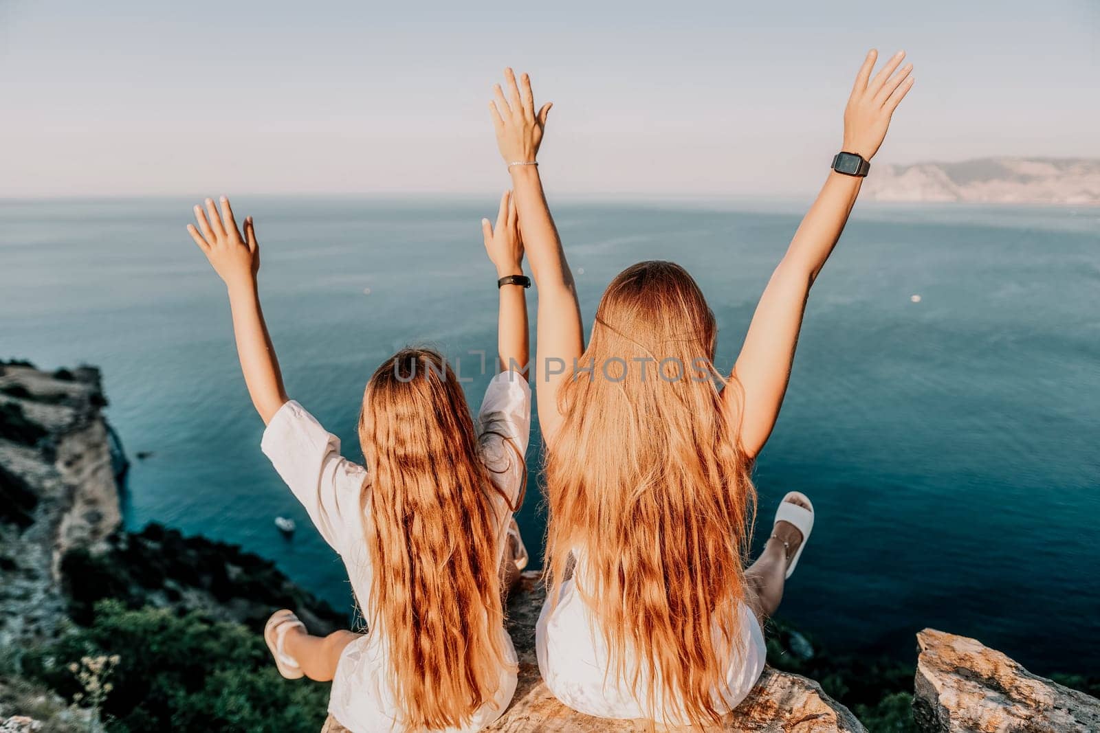 Sea family vacation together, happy mom and teenage daughter hugging and smiling together over sunset sea view. Beautiful woman with long hair relaxing with her child. Concept of happy friendly family. by panophotograph