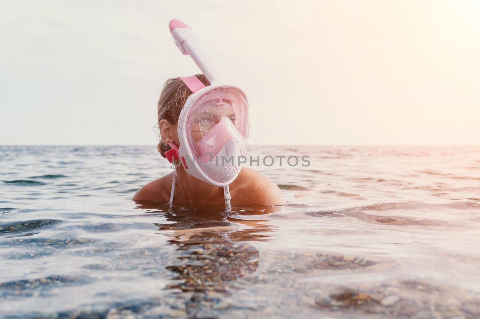 Young happy woman in white bikini put pink snorkeling mask on beach before swimming. girl having fun relaxing on beautiful beach. Beach lifestyle