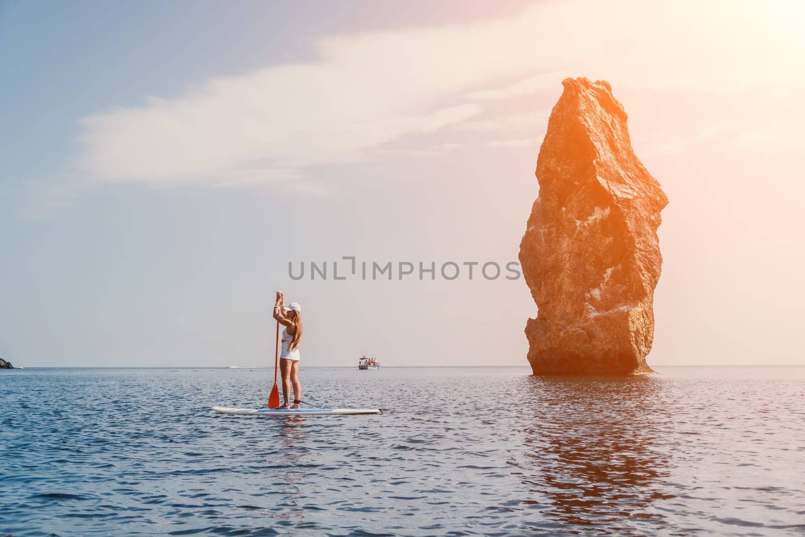 Close up shot of beautiful young caucasian woman with black hair and freckles looking at camera and smiling. Cute woman portrait in a pink bikini posing on a volcanic rock high above the sea