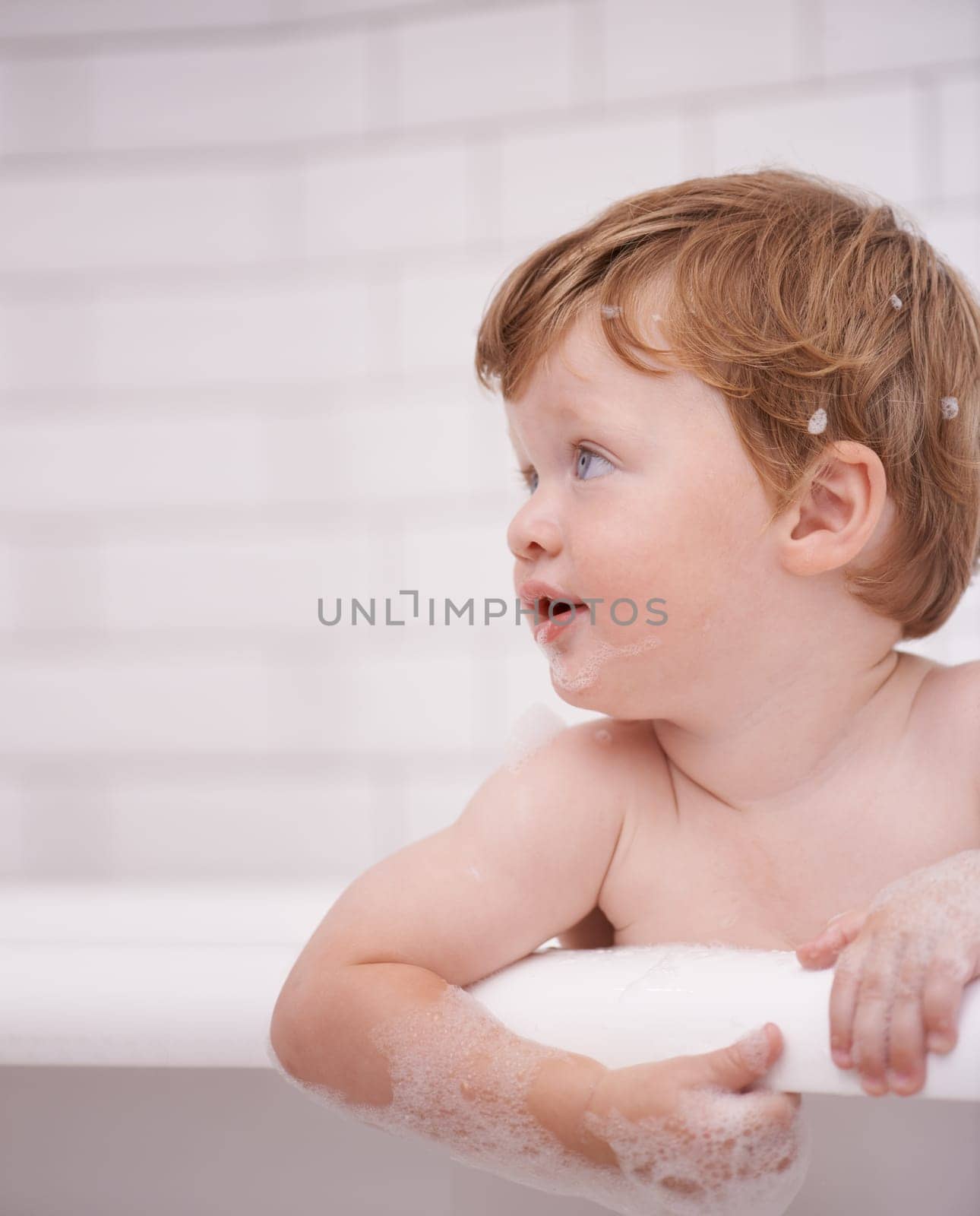 Toddler in bathtub, cleaning with bubbles and soap for morning routine with health, wellness and body care. Male baby washing in foam with hygiene or boy child thinking in water to relax in bathroom.