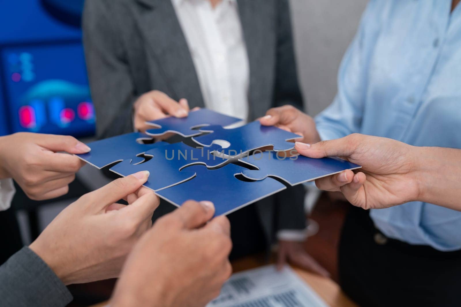 Corporate officer worker collaborate in office, connecting puzzle pieces with report paper on table as partnership and teamwork. Unity and synergy in business concept by merging jigsaw puzzle. Concord