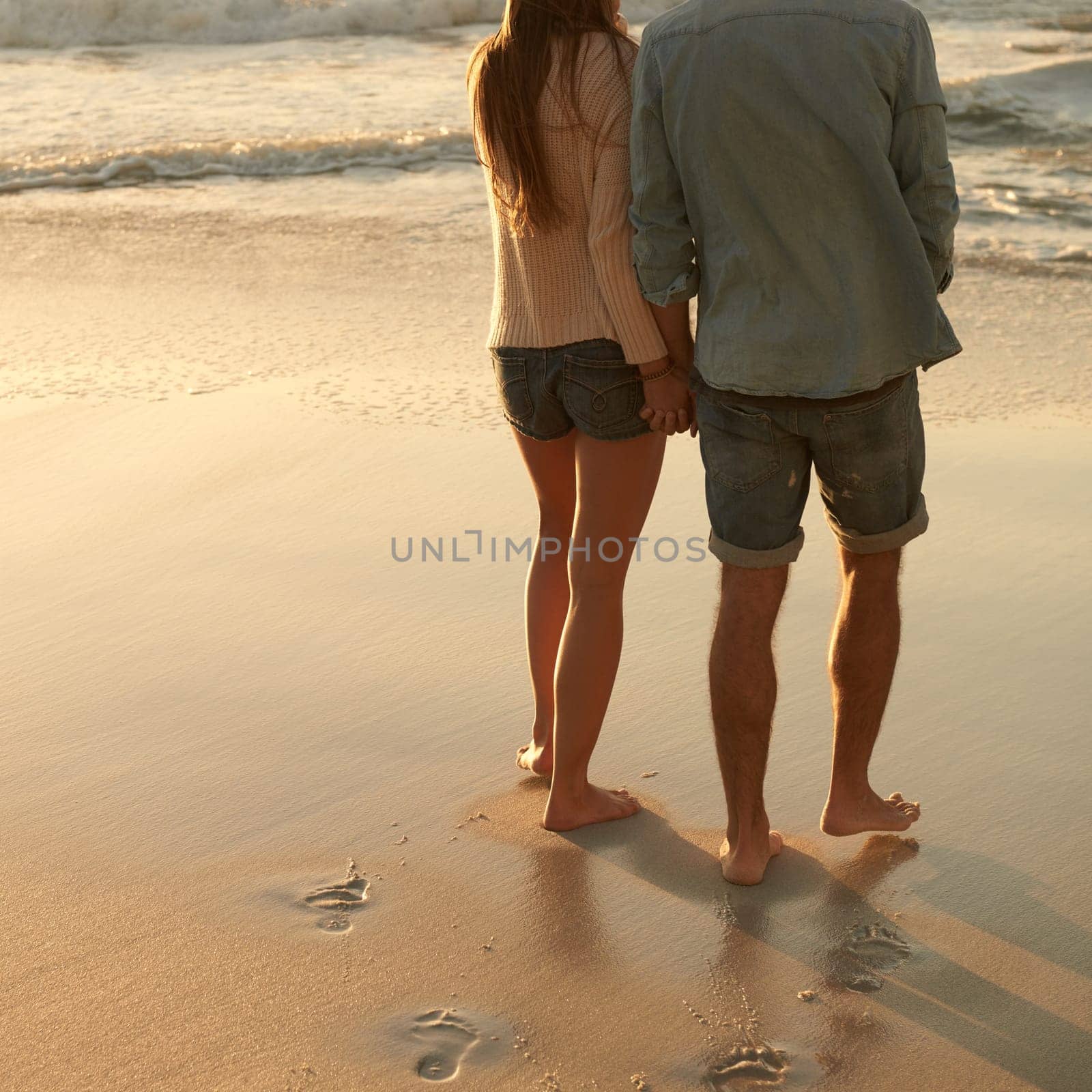 Beach, sunset and couple holding hands with love, support and relationship security on summer holiday in Portugal. Mockup space, sand and back of partner, soulmate or people on evening walk together.