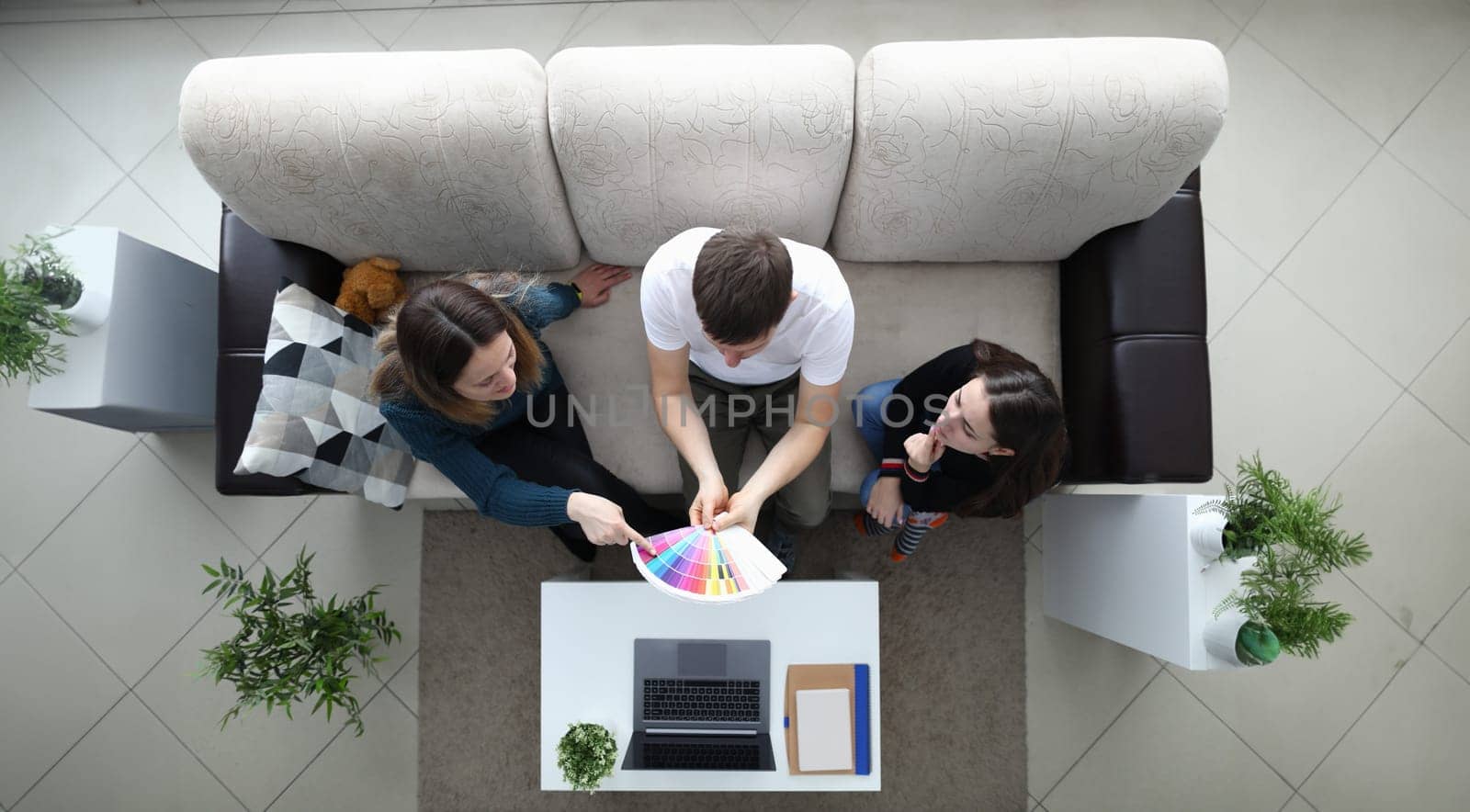 Girlfriends choose color from palette guy holds. Girls choose color for painting walls in room during quarantine. Friends discuss future color. Acquisition new skills during self-isolation