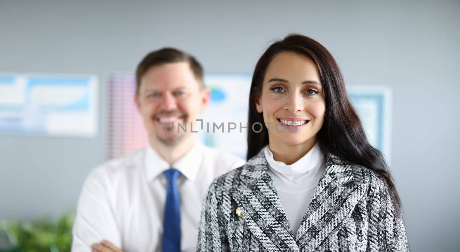 Smiling employees man and woman stand in office. Creating favorable psychological climate in team. Strict control when performing certain tasks. Employees feel safe and confident in future