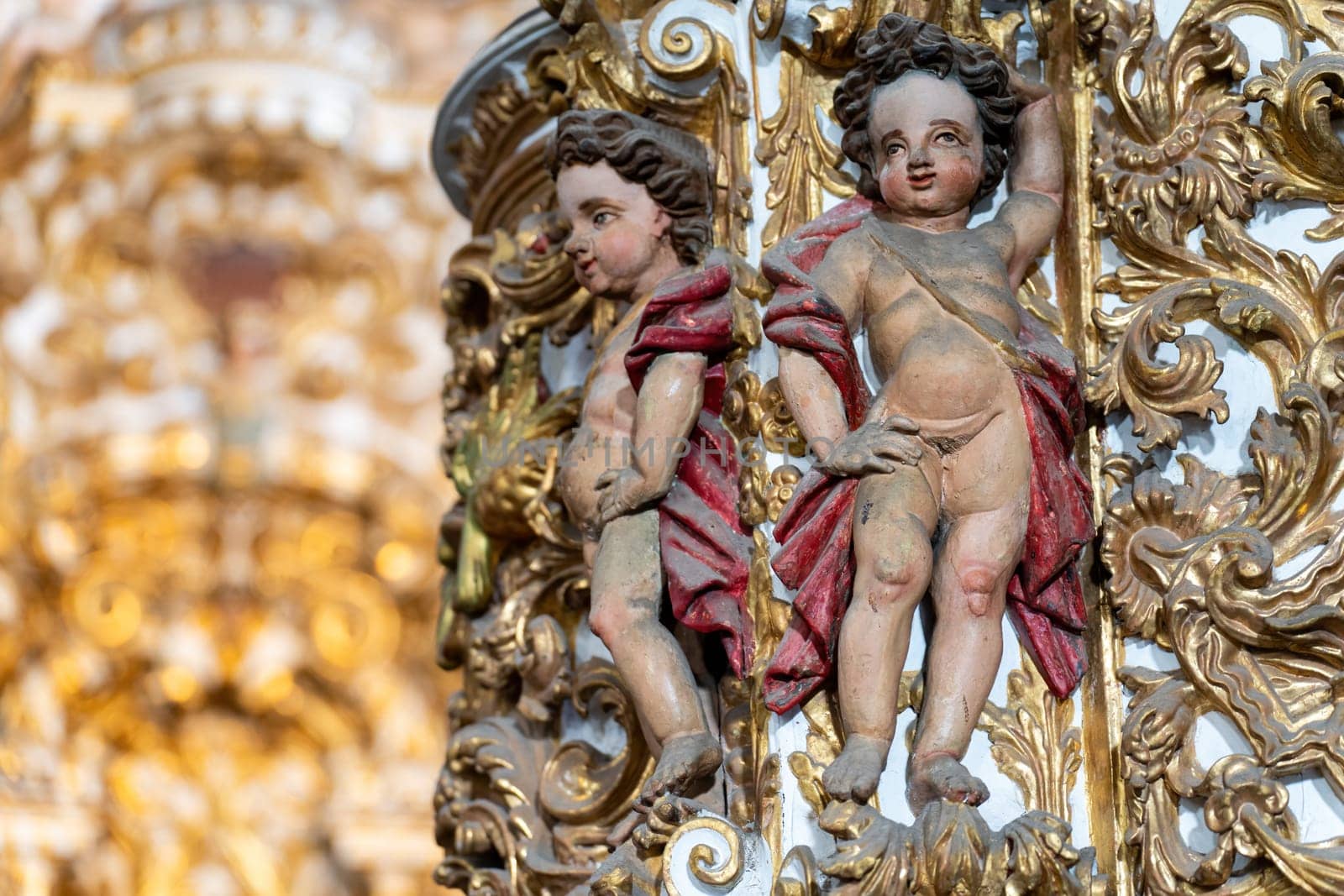 Two cherubs in detailed gilded baroque carvings.