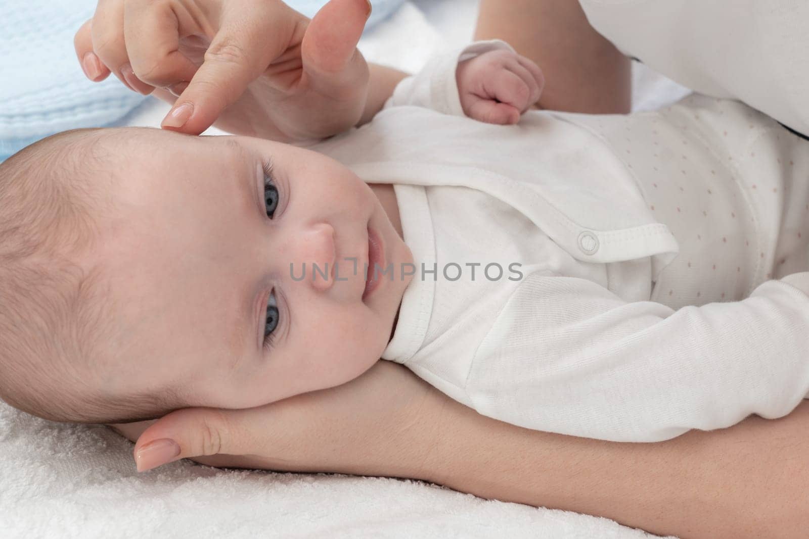 The mother gently touches the baby's head with her finger