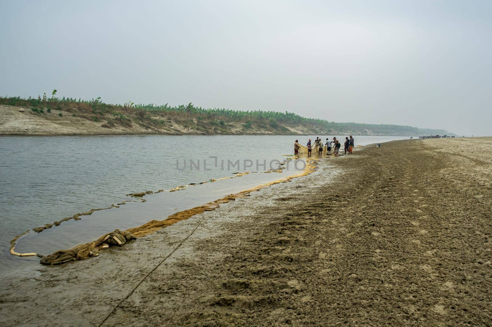 31.12.2023: Bangladesh - Small group of people fishing in river with net