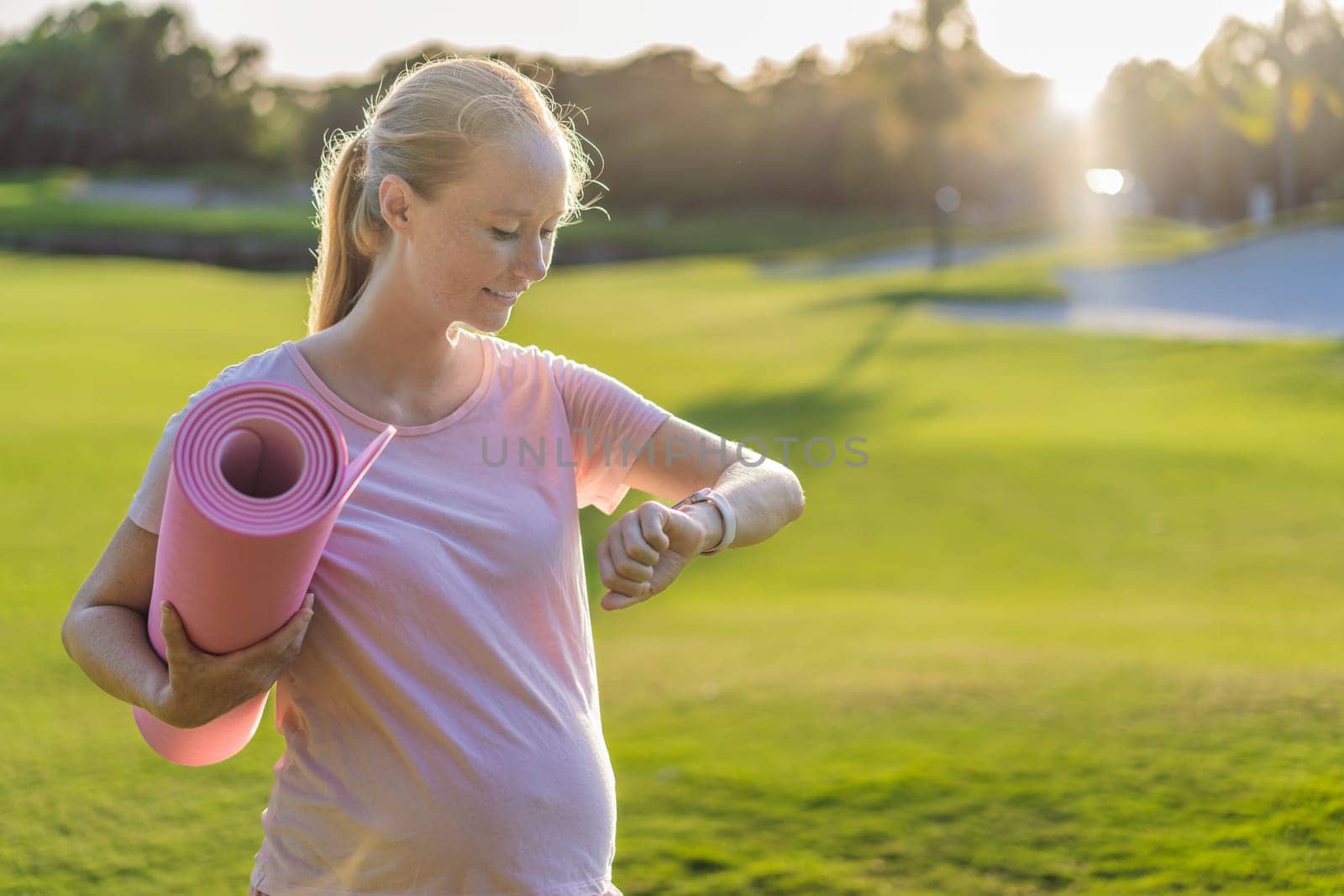 Energetic pregnant woman takes her workout outdoors, using an exercise mat for a refreshing and health-conscious outdoor exercise session.