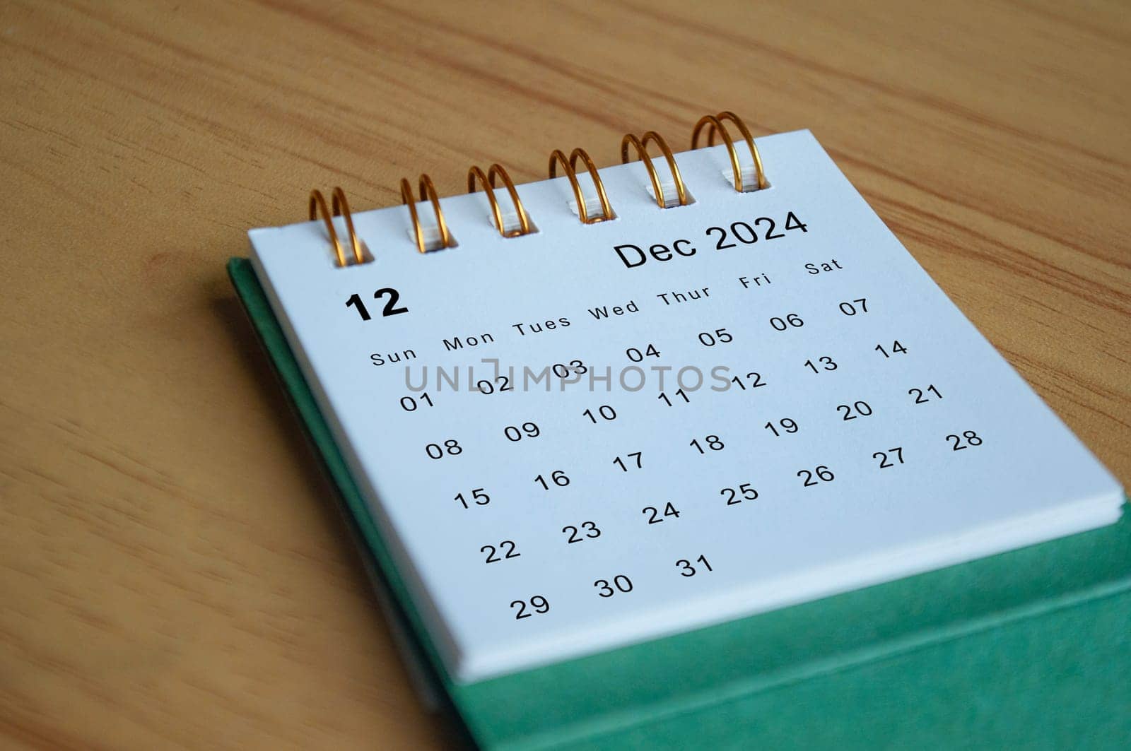Close up side view of December 2024 calendar on wooden desk. Calendar concept.