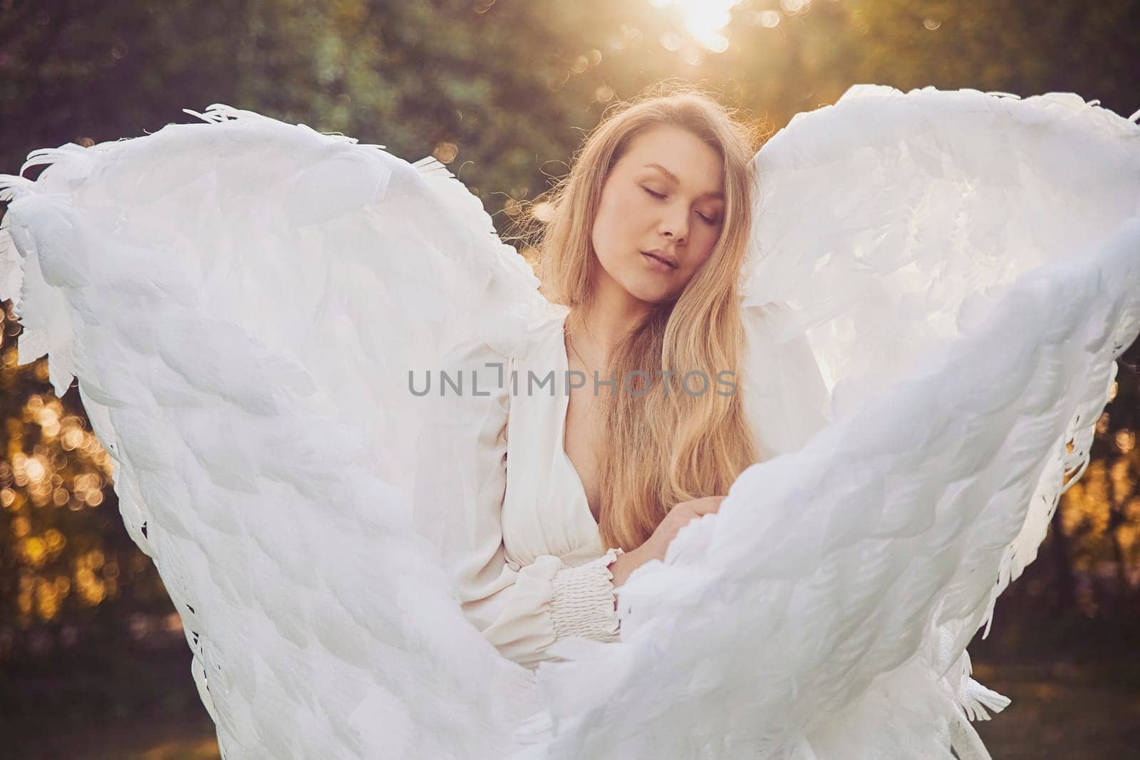 Beautiful girl dressed as an angel in the evening garden.