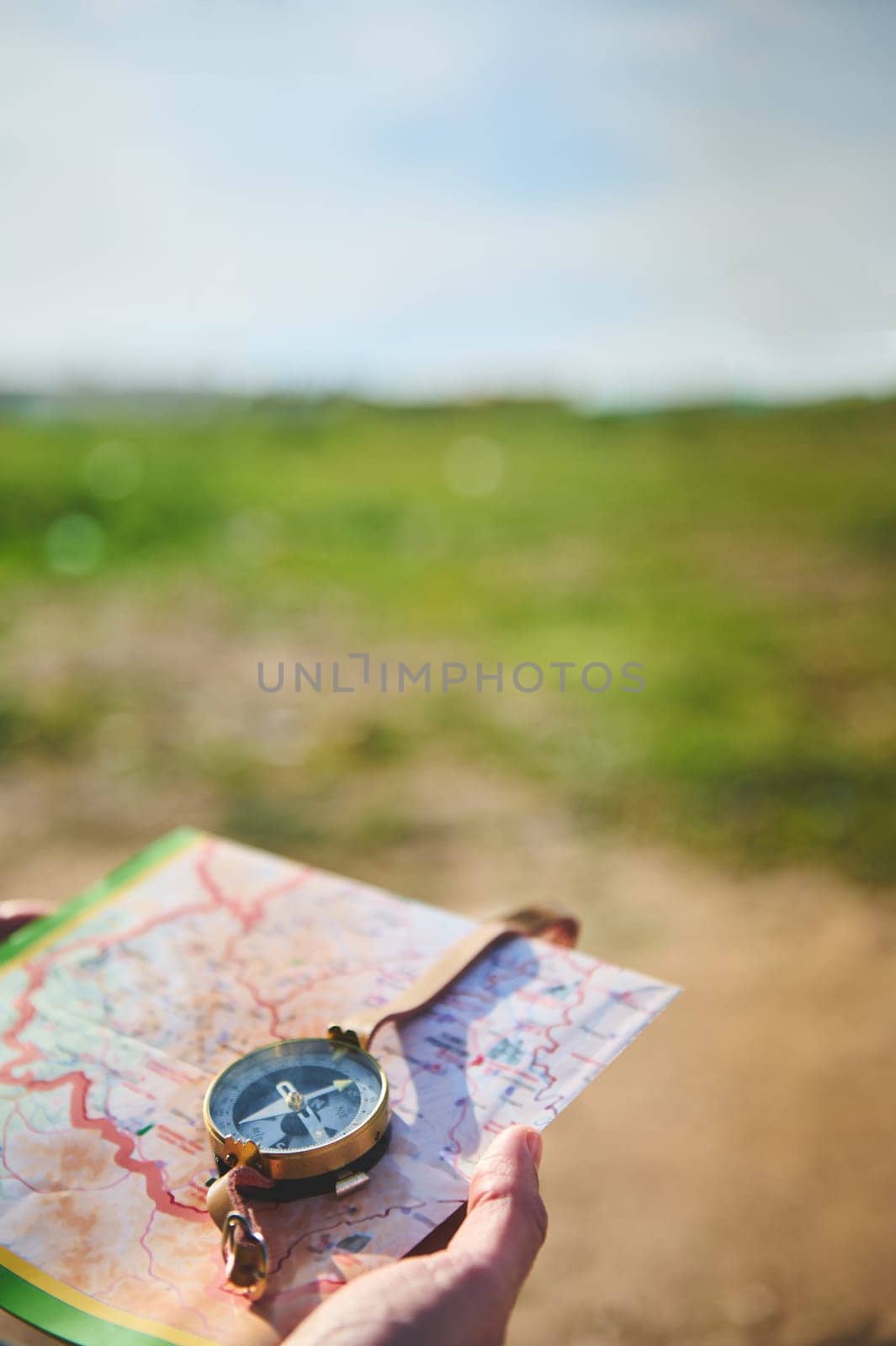 Close-up of a tourist hand holding a compass - stock photography concepts. A male hand, a tourist adventurer hiker uses map and compass to plot course. Copy Advertising space. Tour tourism