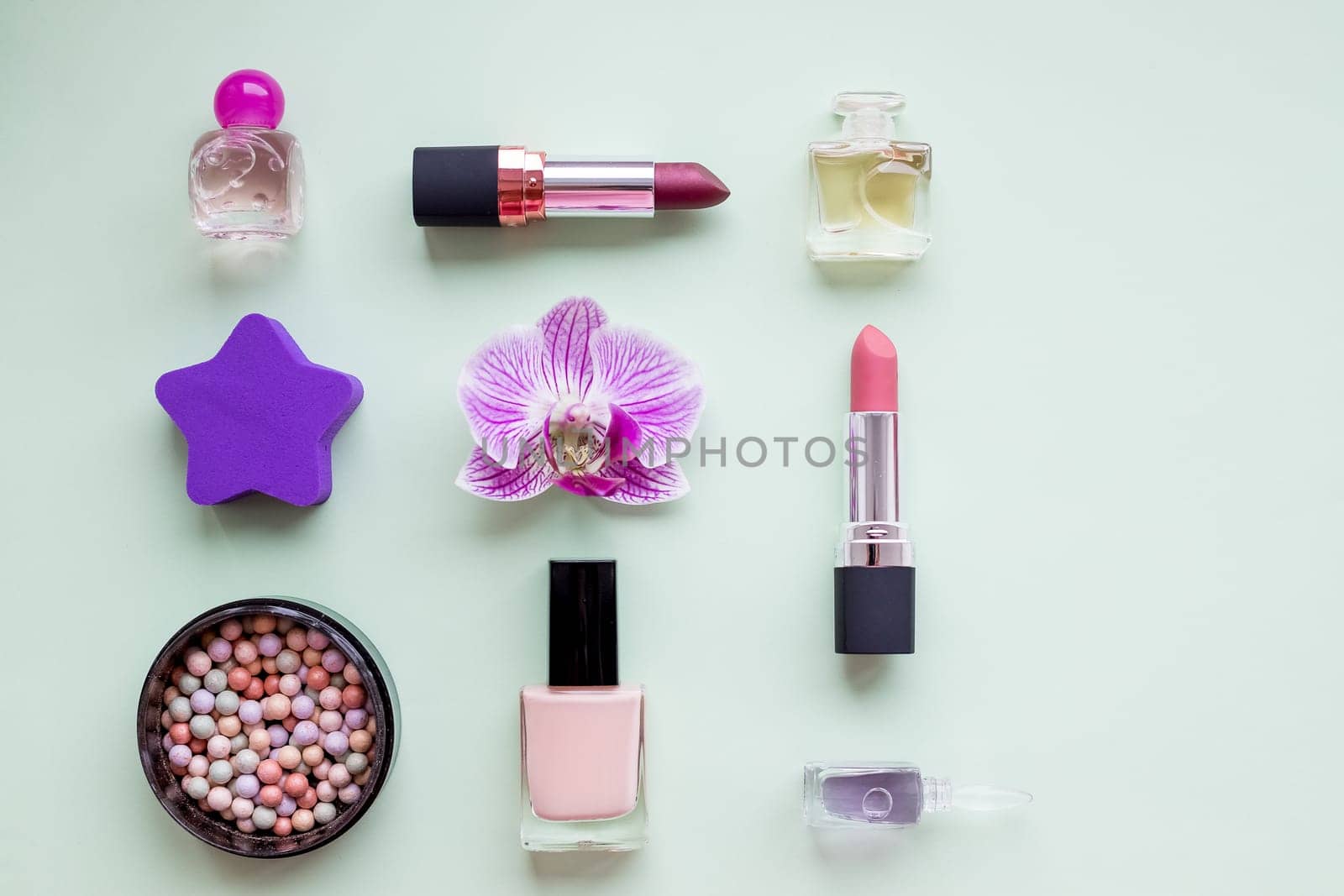 Creative flat lay of fashion bright nail polishes and decorative cosmetic on a colorful background. Minimal style.