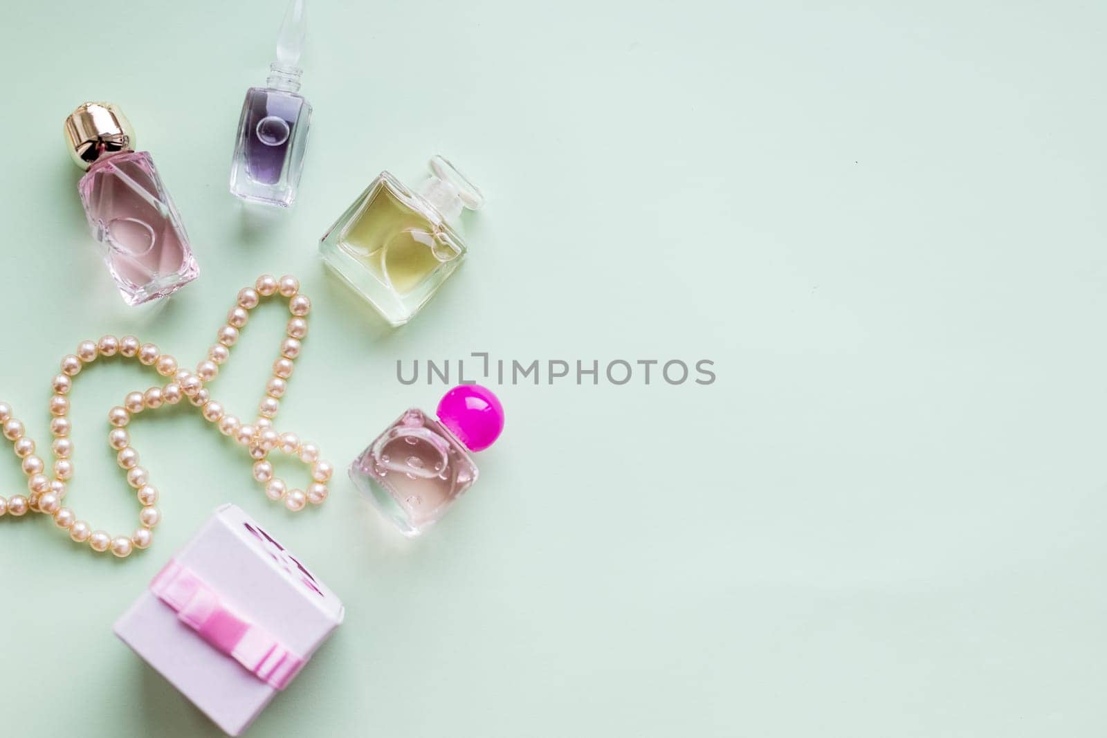 Flat lay for fashion blogger. Woman's glamour makeup beauty products on pastel background. Perfume, present box and pearl necklace. Elegant style.Transparent bottles of perfume ,Copy space by YuliaYaspe1979