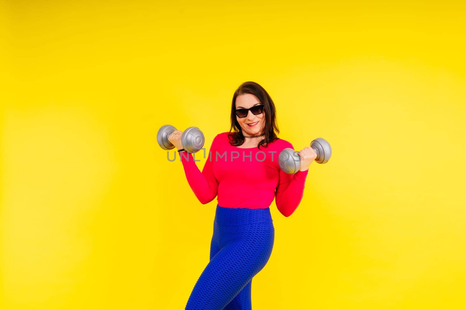 Young smiling happy chubby overweight plus size big fit woman warm up training hold dumbbells