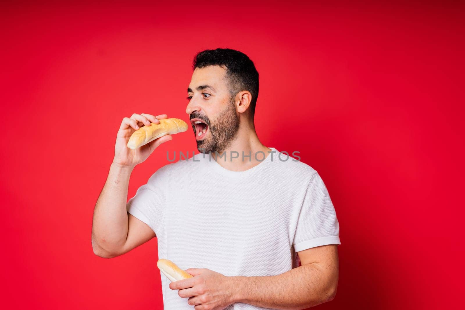 Man holding freshly baked bread in hands isolated on a red background