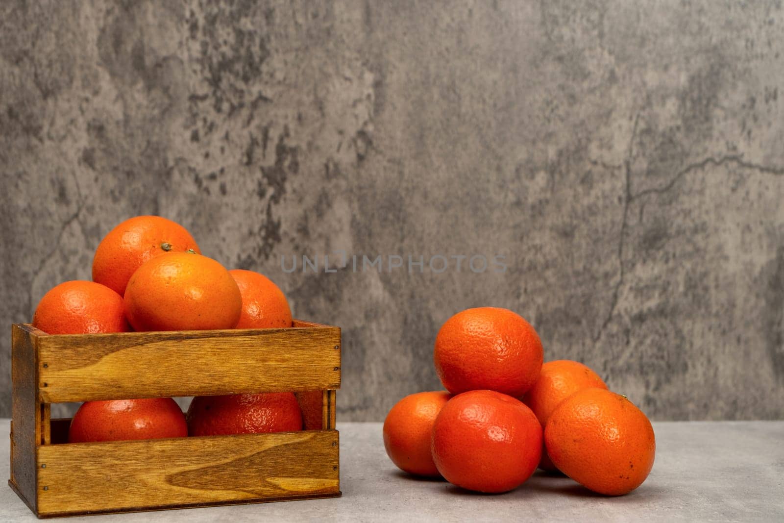 Product image with a wooden basket full of oranges and a few more in a pile, isolated on a gray background. Vitamin c, superfood, fresh fruits