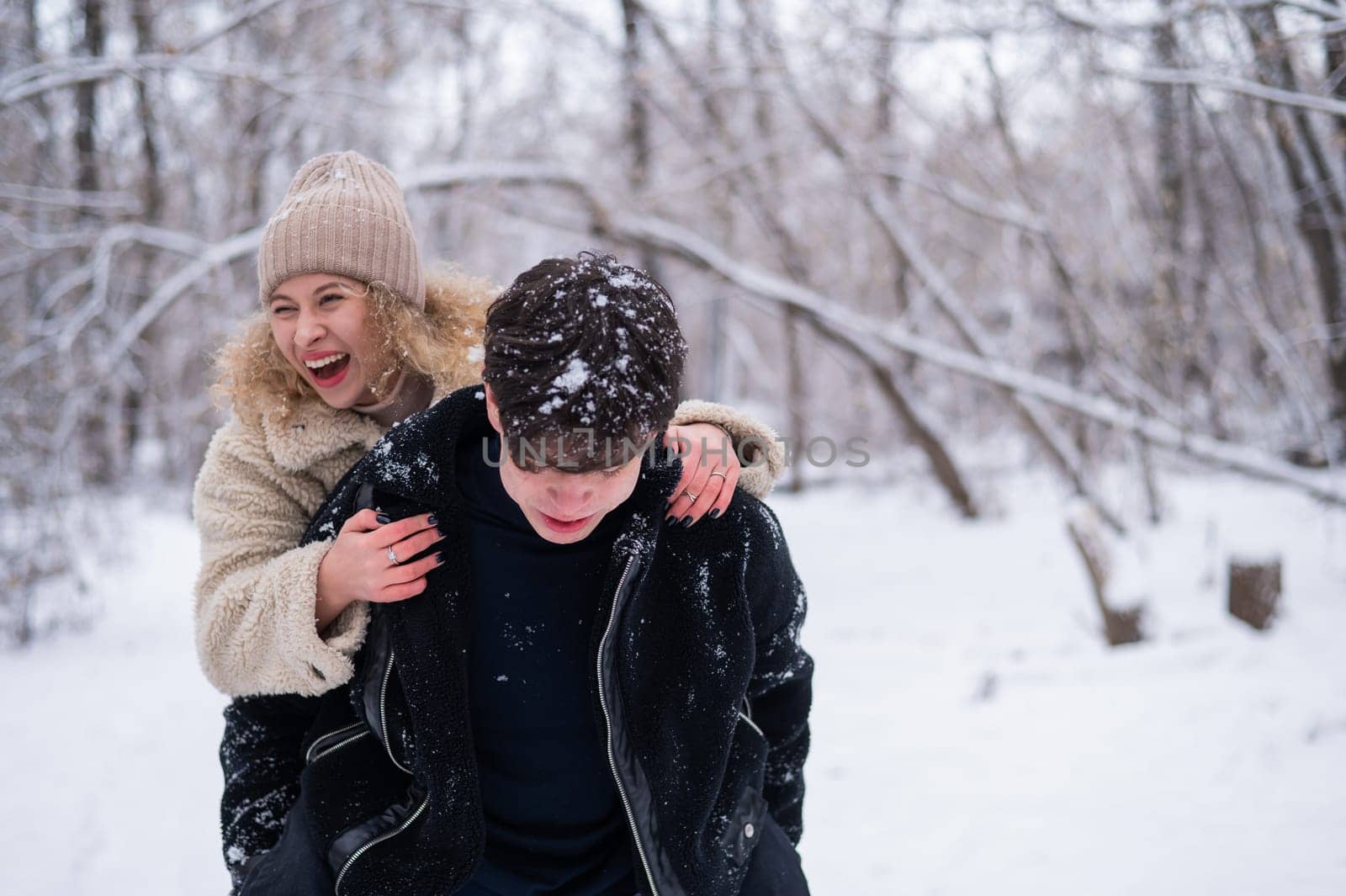 A young couple walks in the park in winter. Guy and girl hugging outdoors