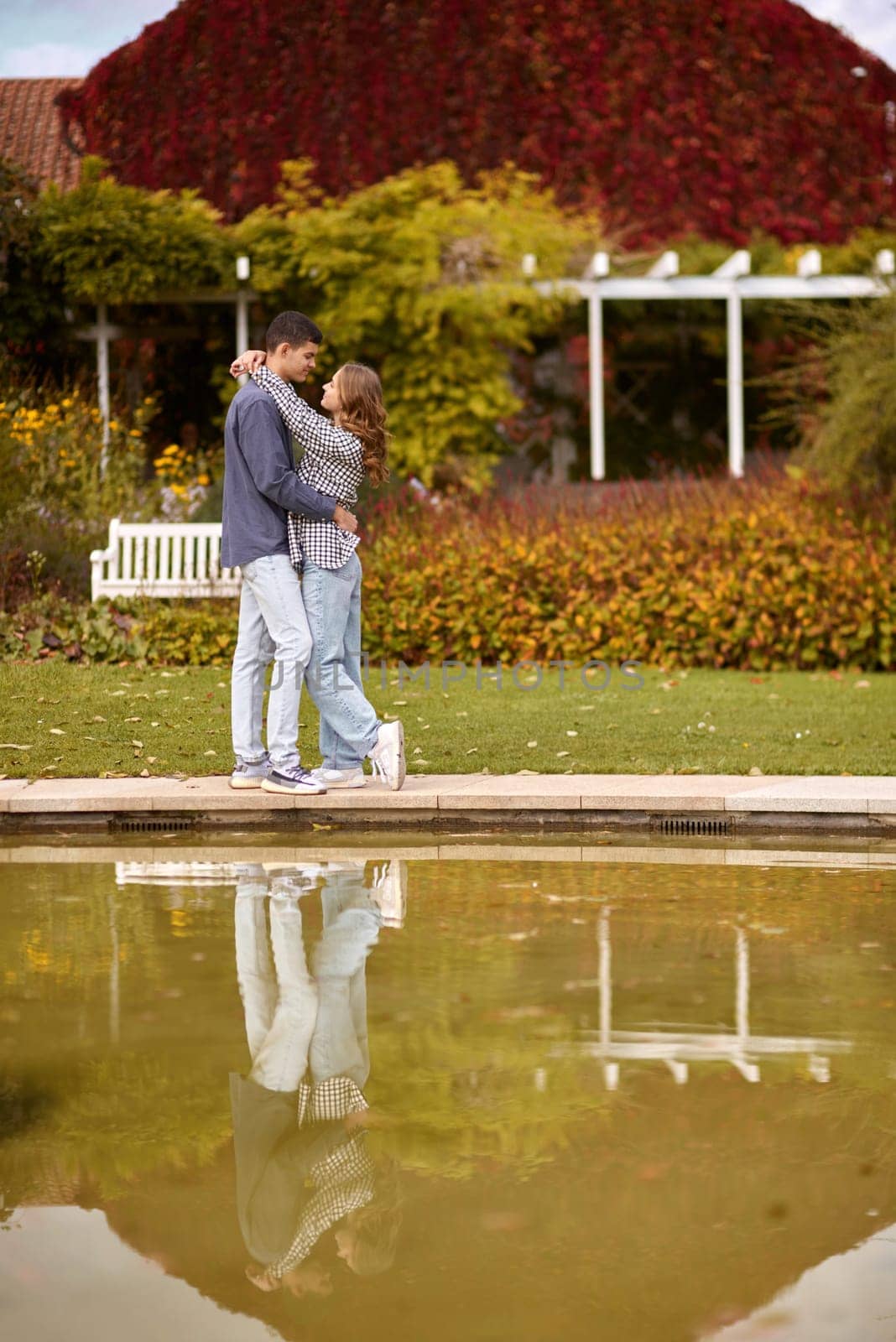 A couple in love hugs on the shore of a city pond in the European town. love story against the backdrop of autumn nature. Embraced by Love: Couple by the City Pond in a European Town. Autumn Affair: Romance on the European City Pond. Couple's Affection in Autumn by Andrii_Ko