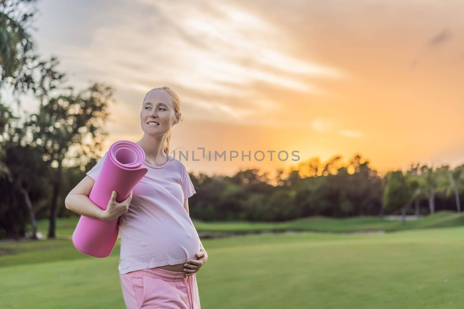 Energetic pregnant woman takes her workout outdoors, using an exercise mat for a refreshing and health-conscious outdoor exercise session.