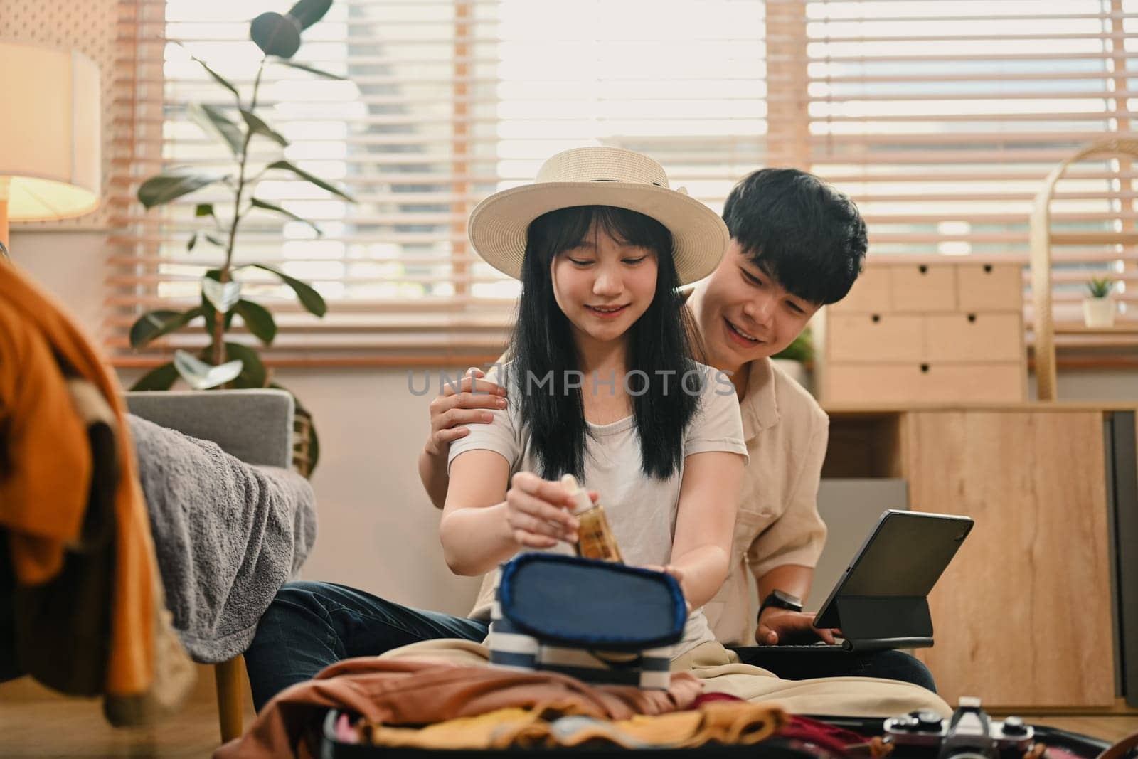 Loving young couple packing clothes into travel bag, getting ready for their holiday trip by prathanchorruangsak