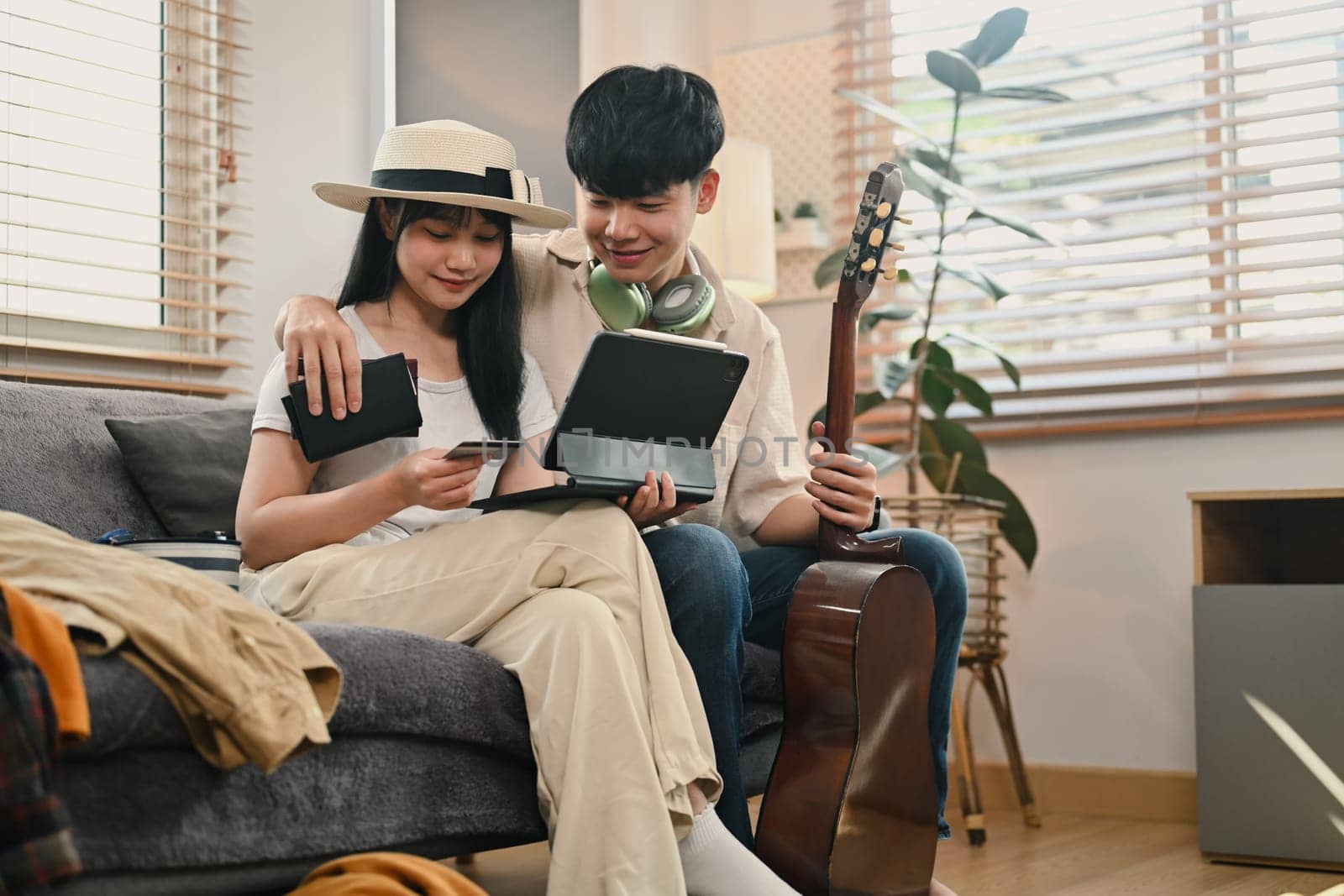 Happy young couple planning holiday trip, buy tickets, purchase flight or book hotel on digital tablet.