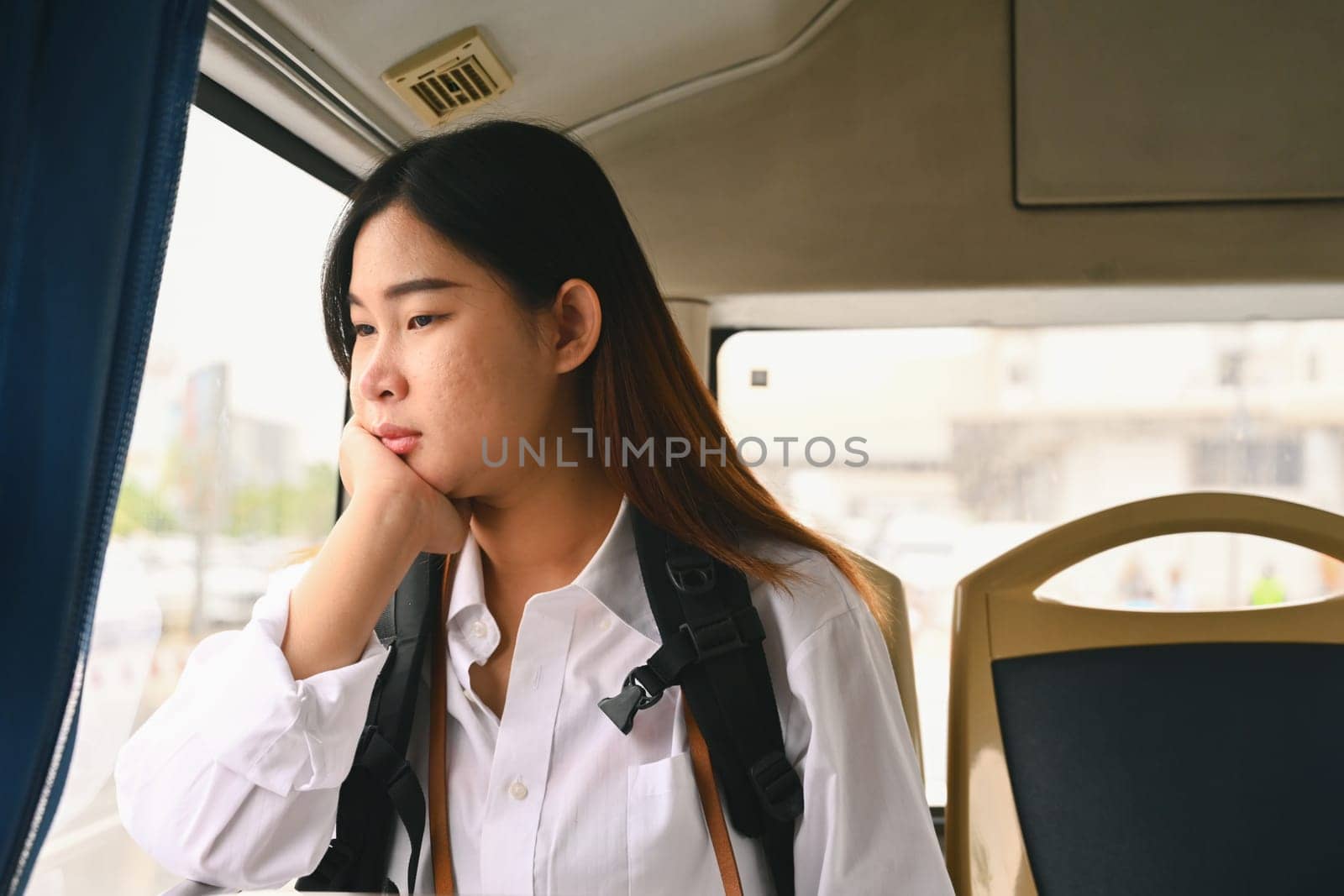 Young woman looking through looking through the window while commuting by bus.