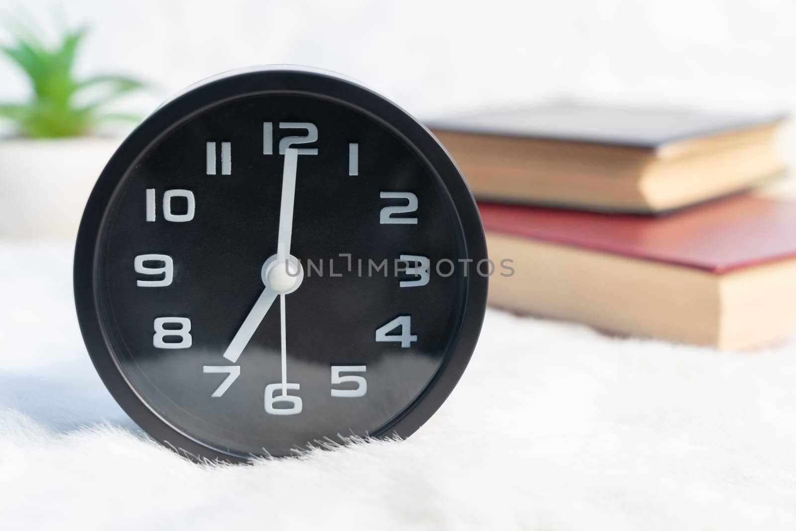 Close up Black alarm clock and book stacked on table